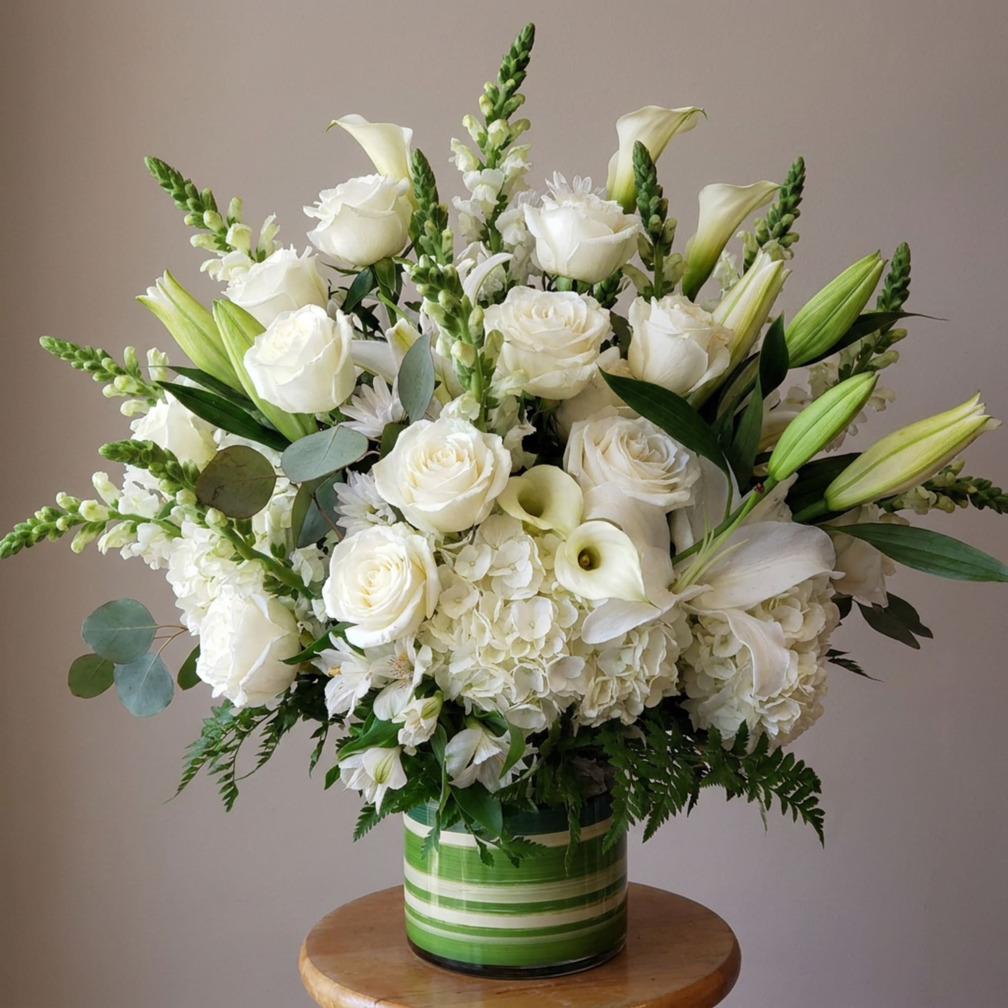 White roses, lilies, and calla lilies in a green striped vase