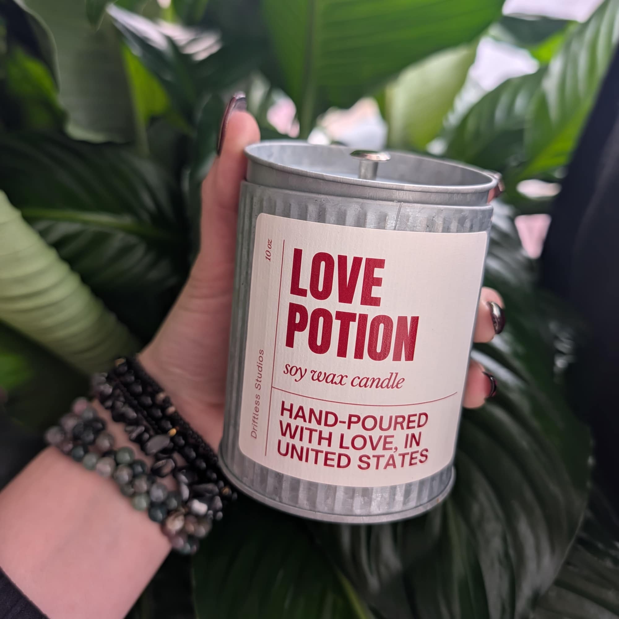 Handheld soy wax candle in a metal tin labeled Love Potion