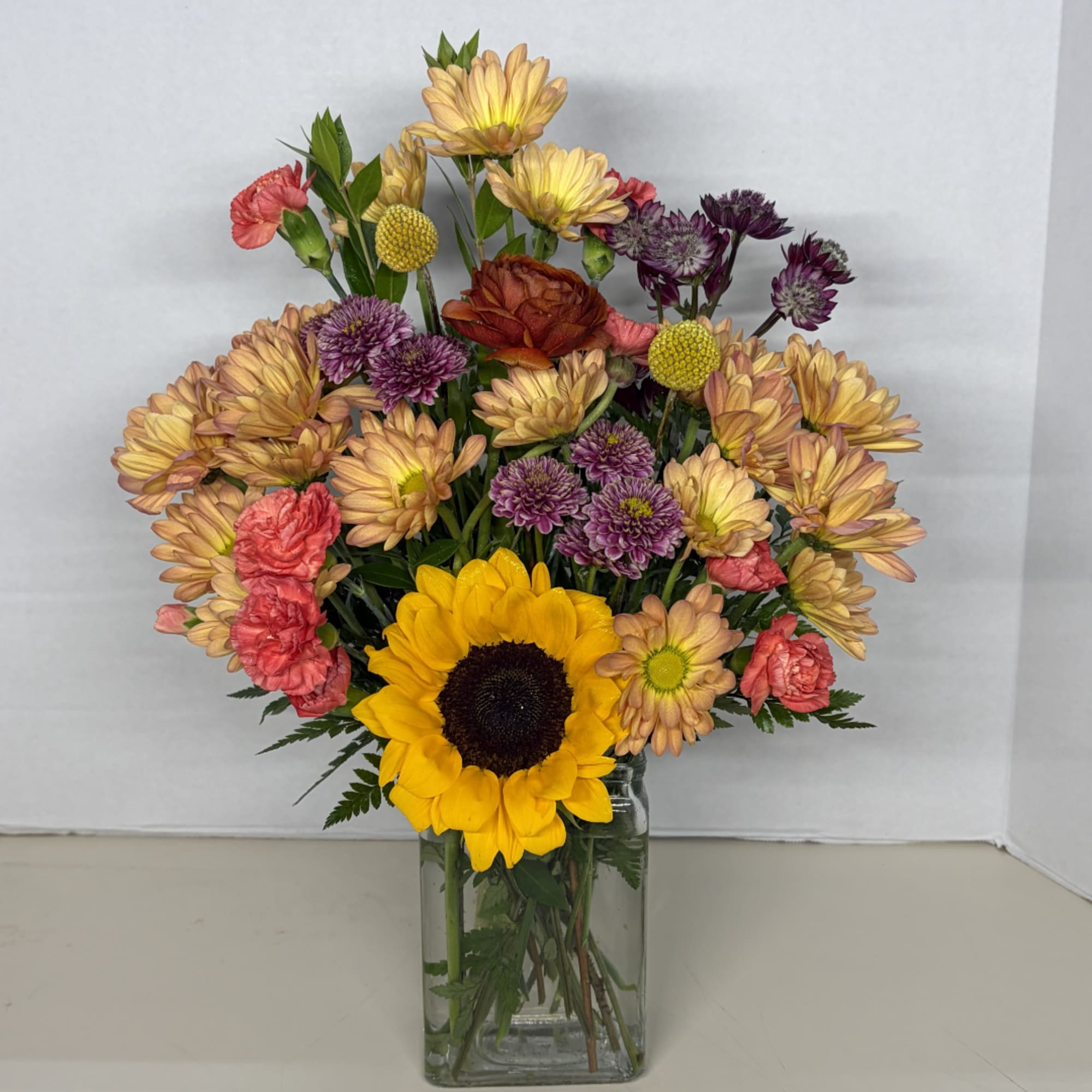 Mixed bouquet with a sunflower in a clear glass vase