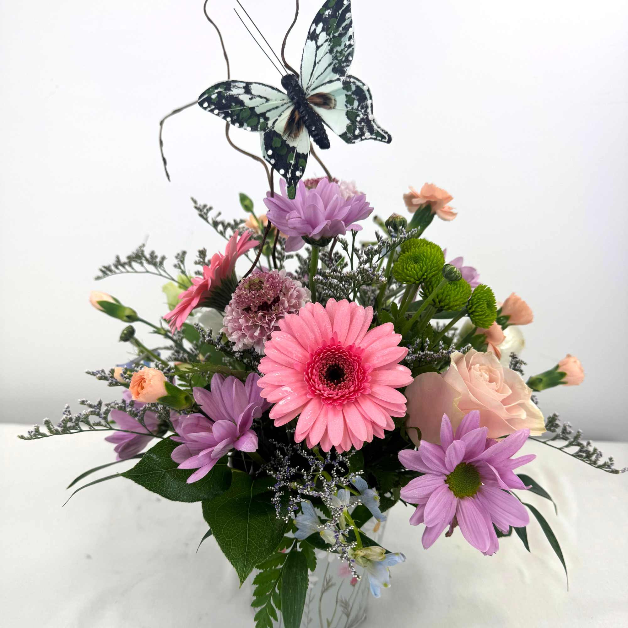 Bright coral gerbera daisies take center stage in this pastel garden-style flower