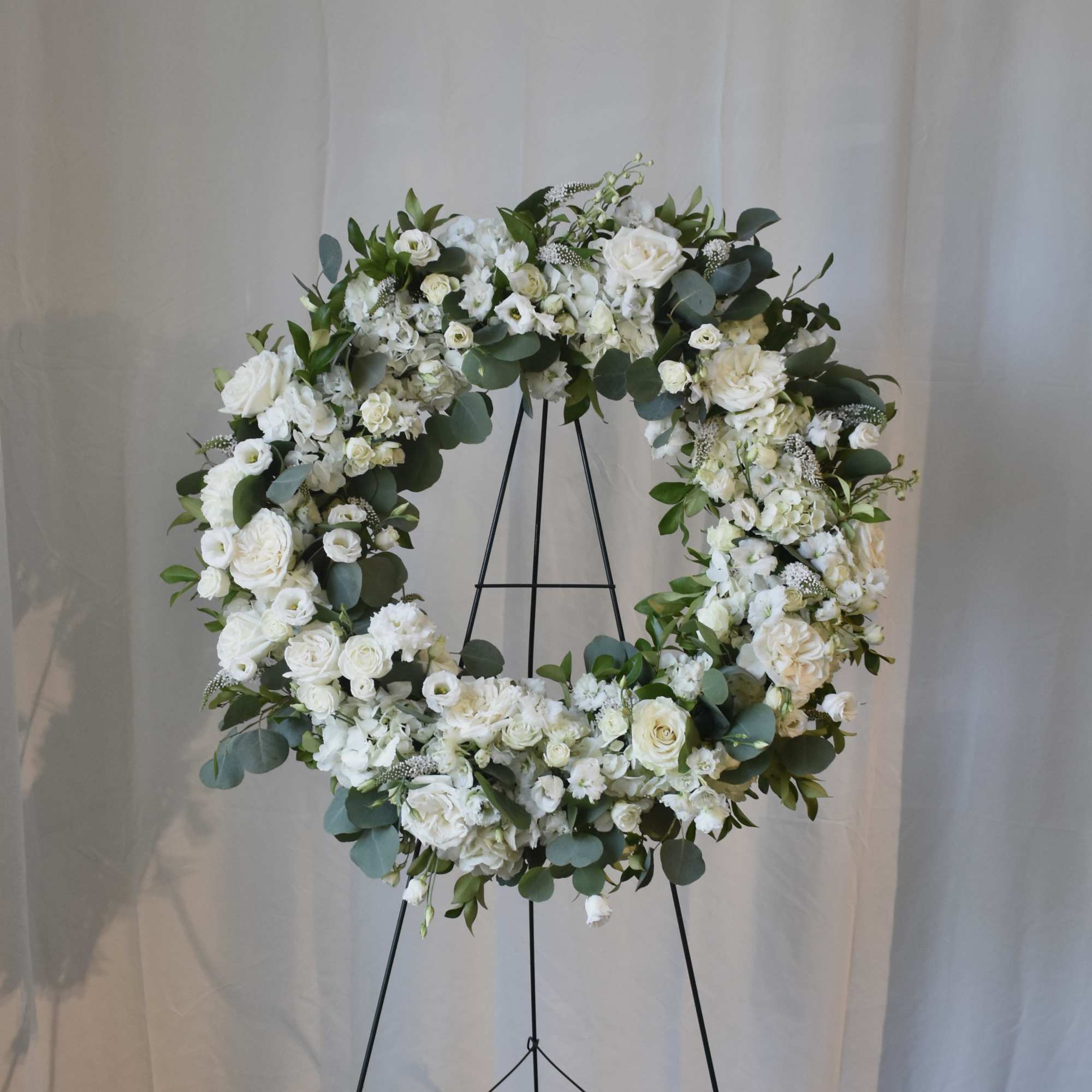 White floral wreath on a black stand