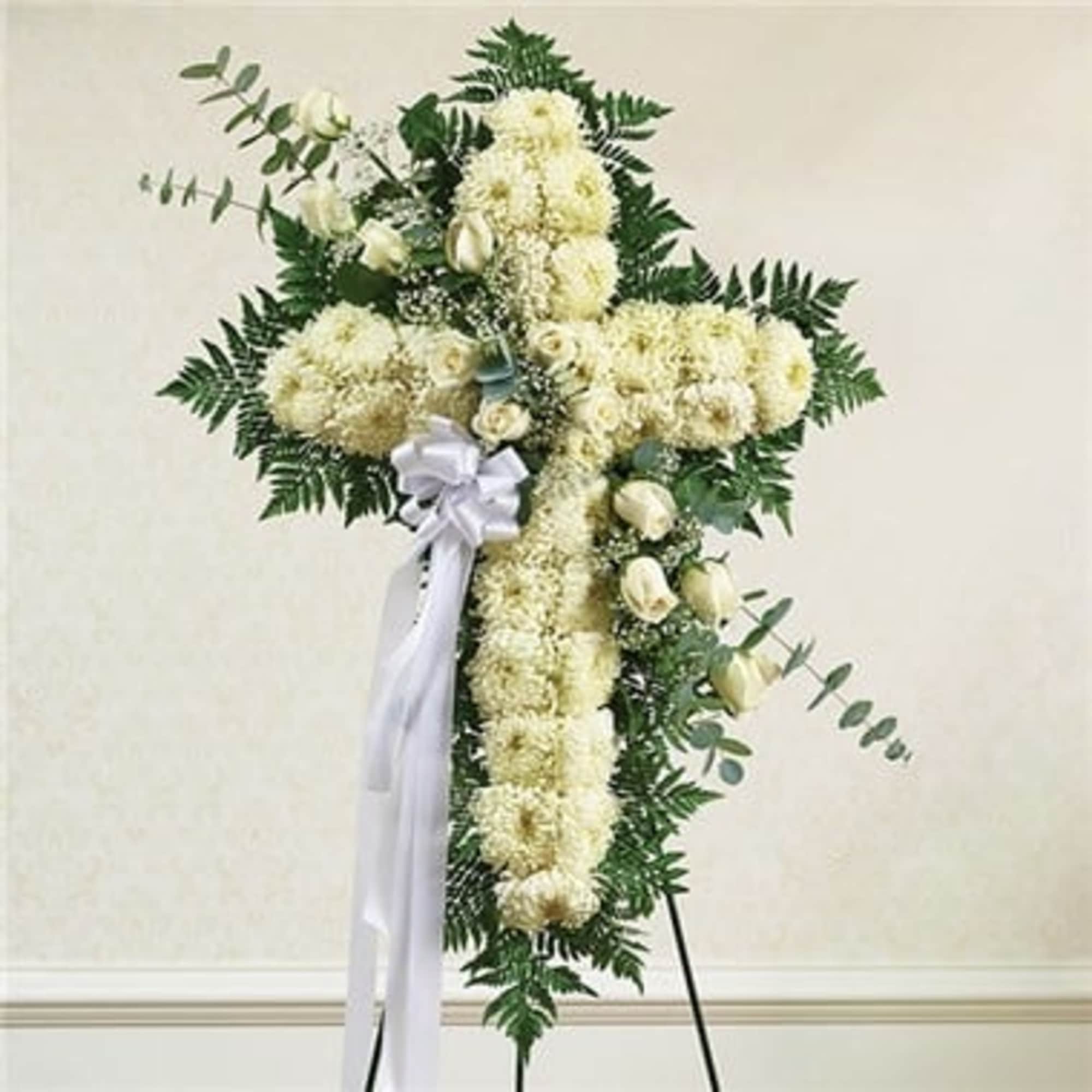 White floral standing cross with ribbon and greenery