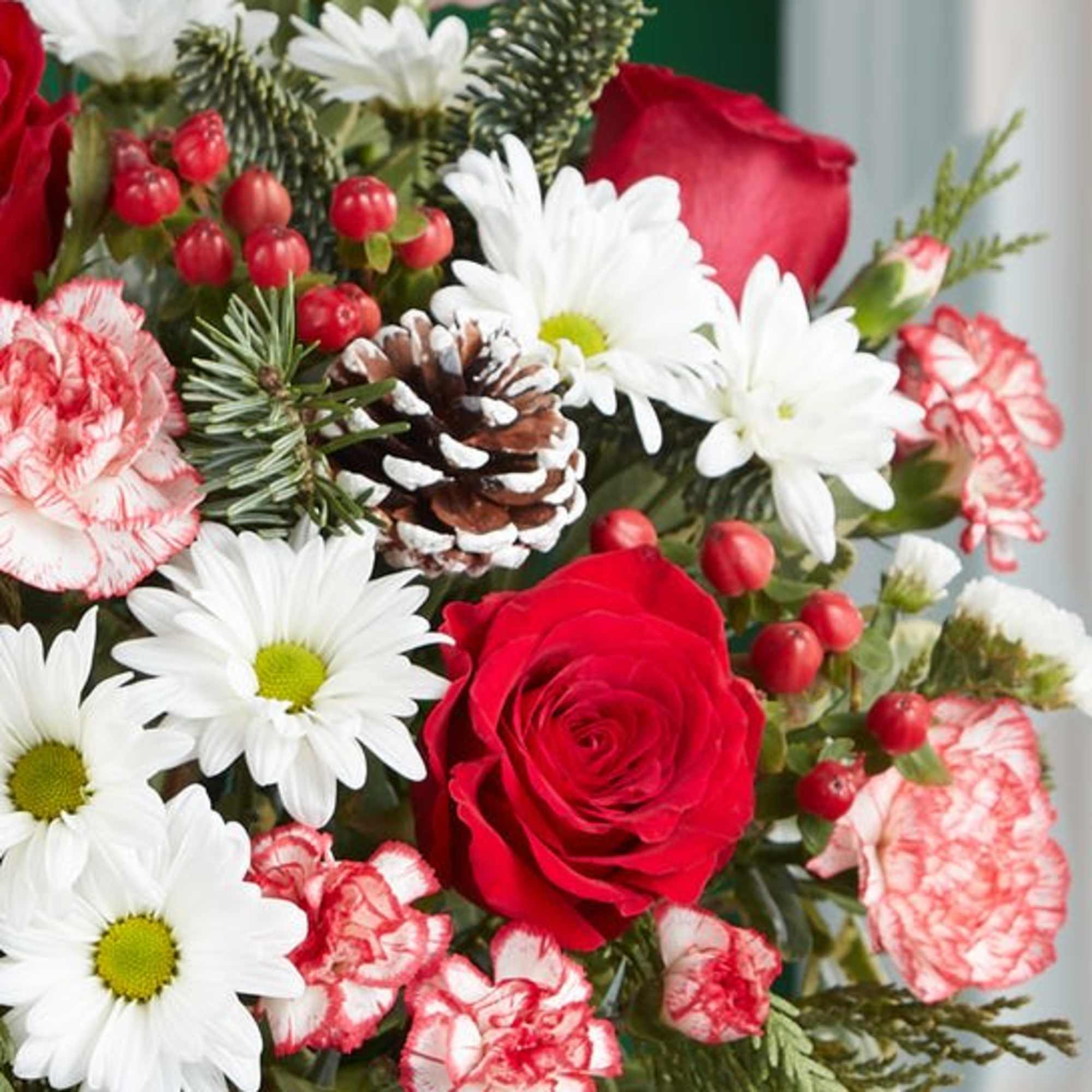 Bouquet of red roses, white daisies, and red-and-white carnations with pinecone accents
