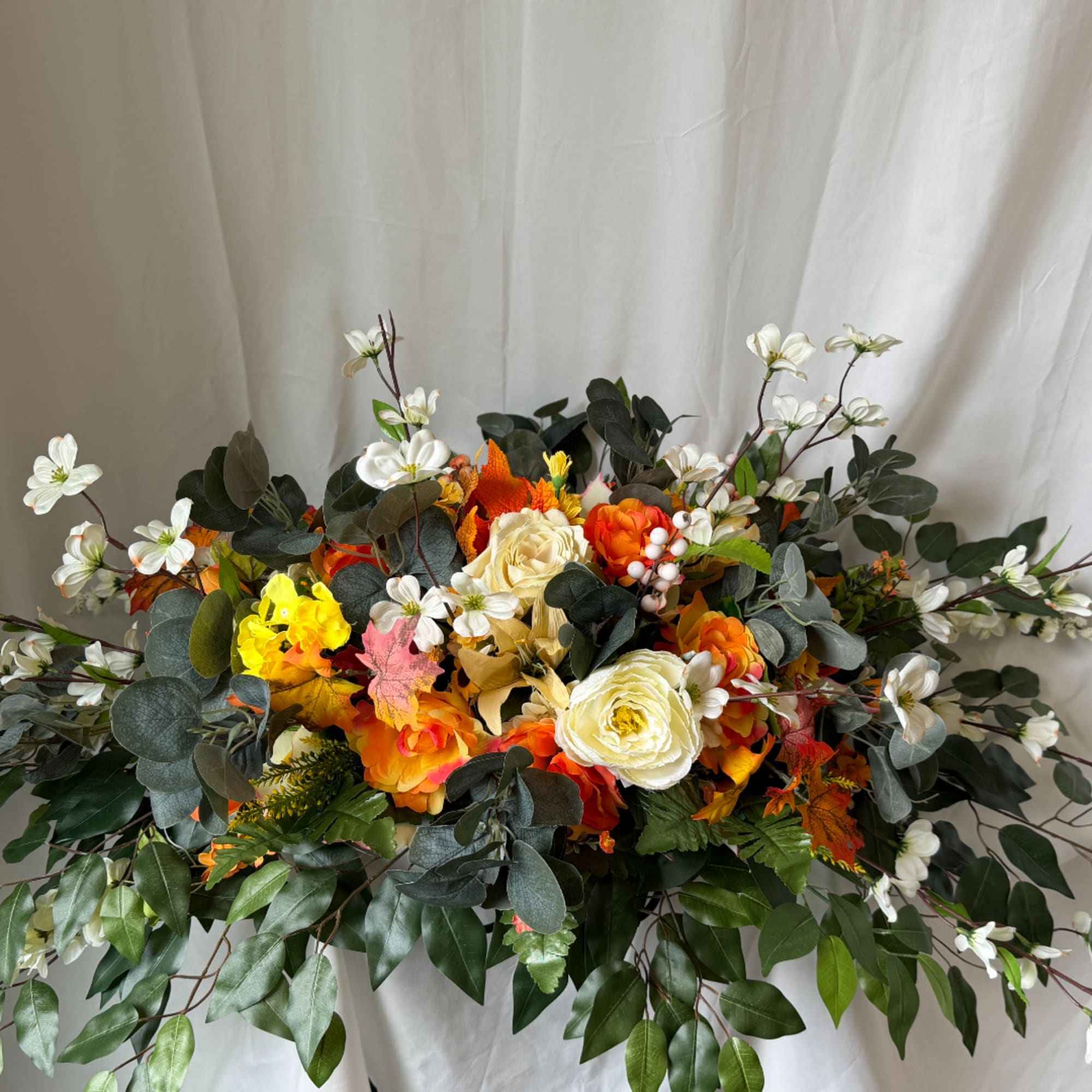 Autumn floral arrangement with white and orange blooms and dark greenery
