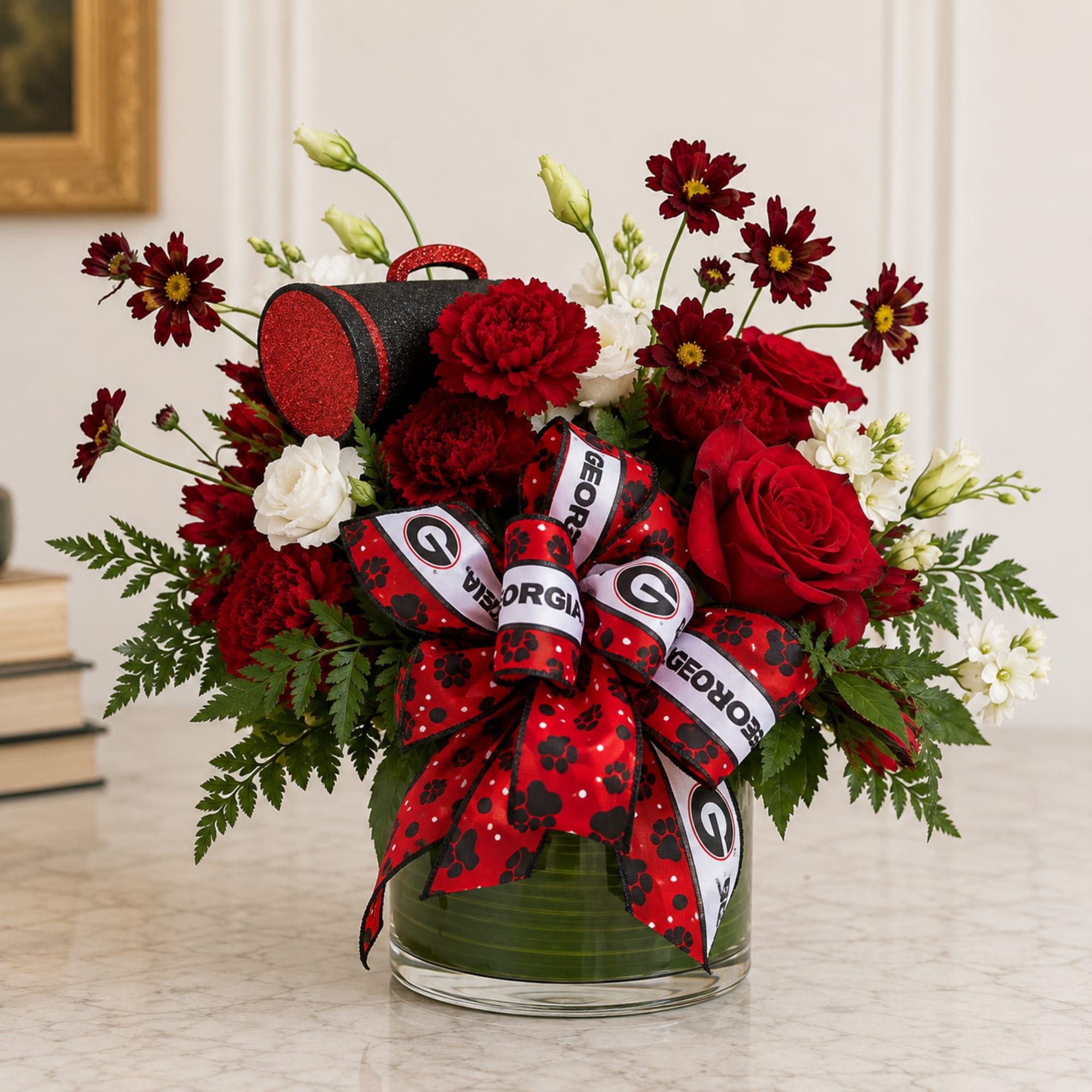 Red and white floral arrangement in a glass vase with a Georgia ribbon