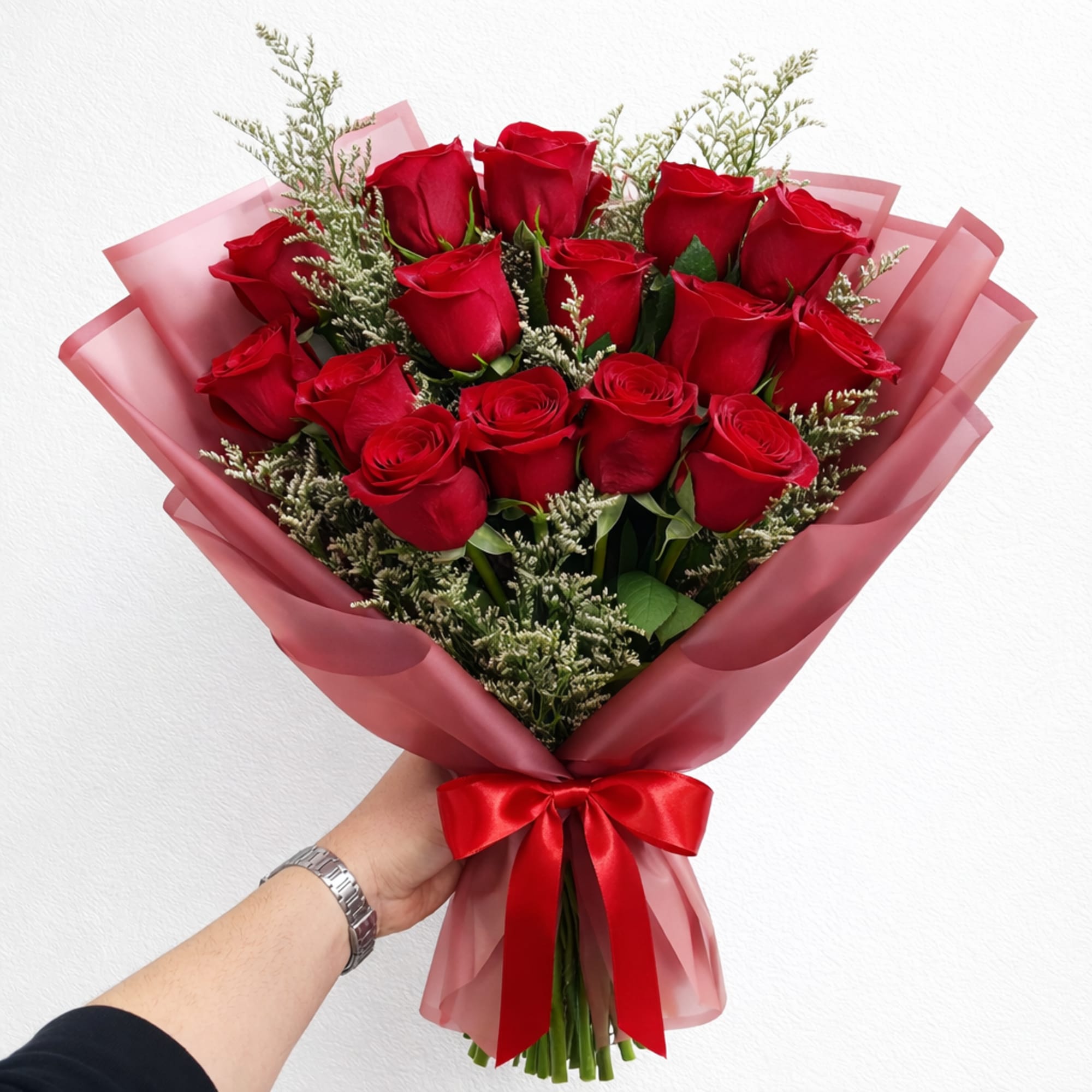 Bouquet of red roses wrapped in pink paper with a red ribbon