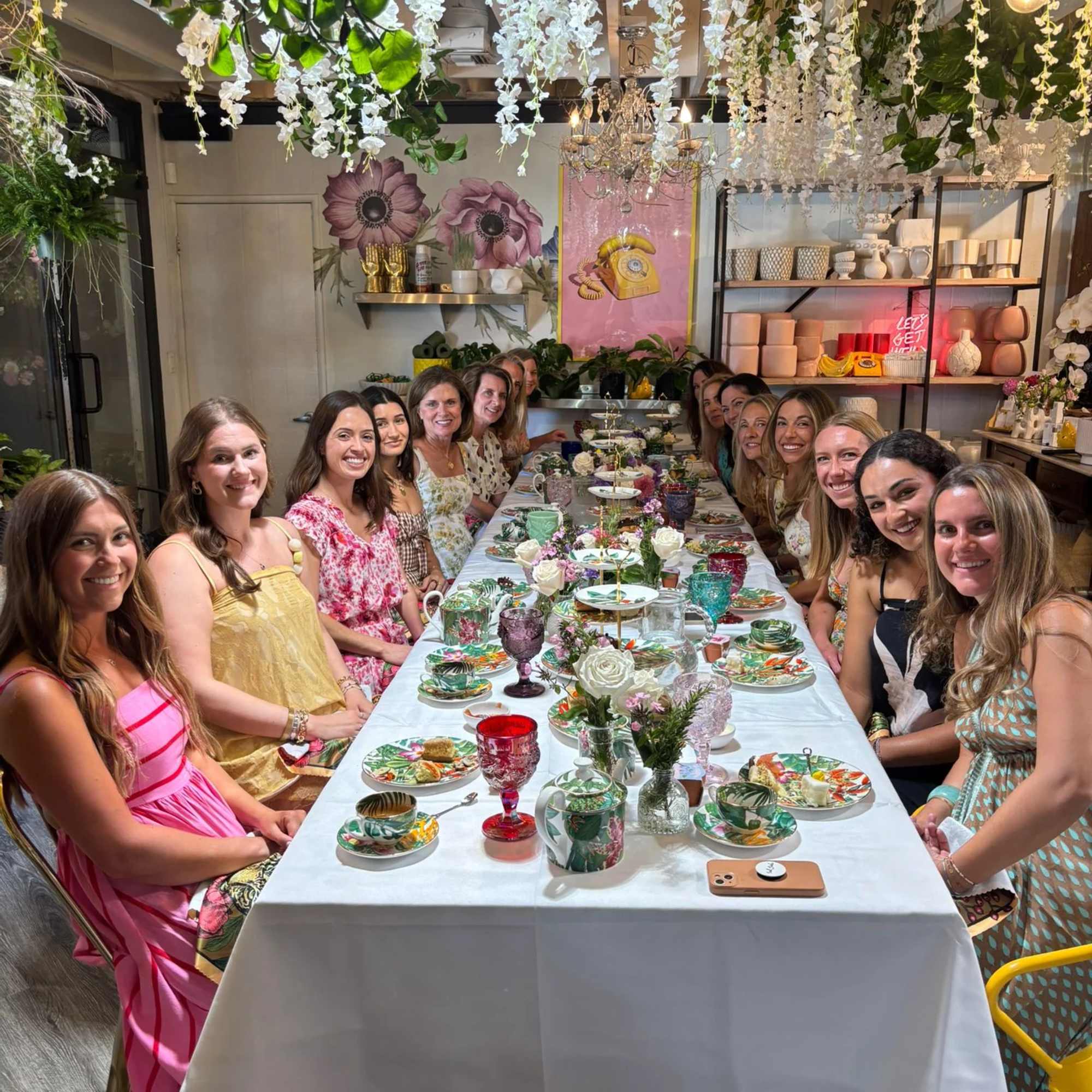 Long table set with small floral centerpieces under hanging white blossoms