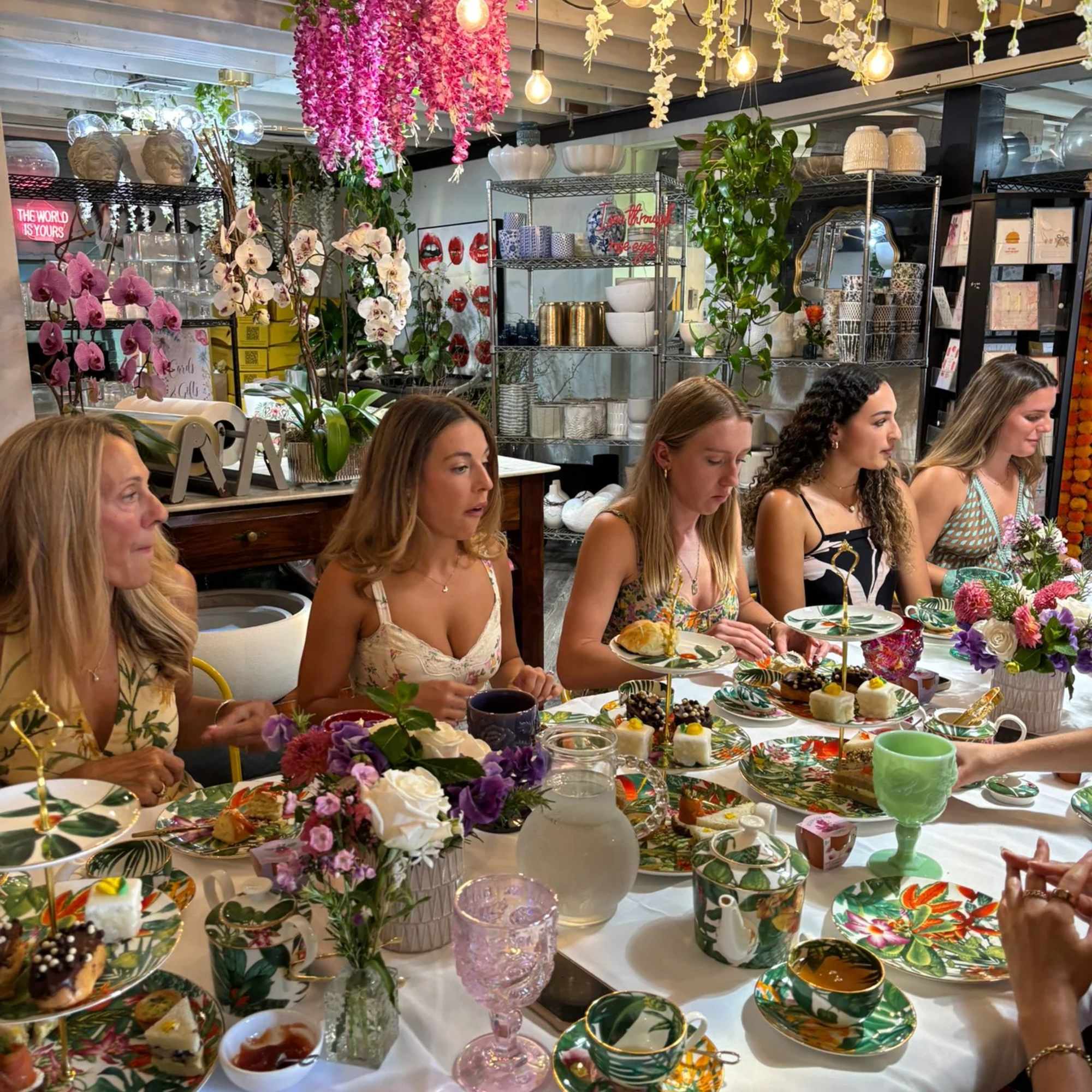 Flower-filled table setting with pink and purple arrangements and hanging blossoms