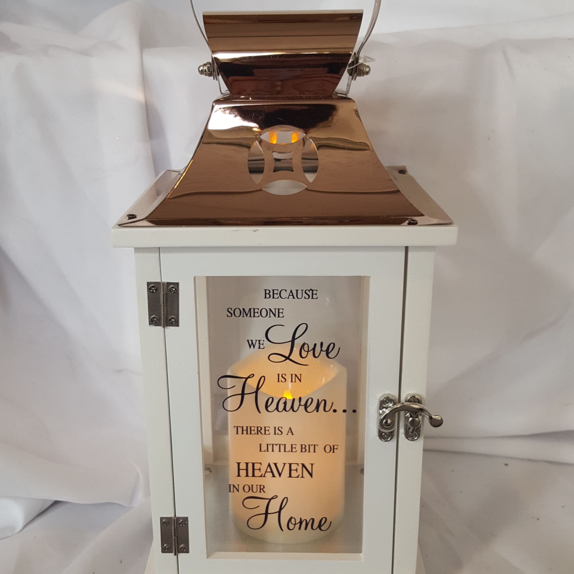 White lantern with a lit candle and memorial text