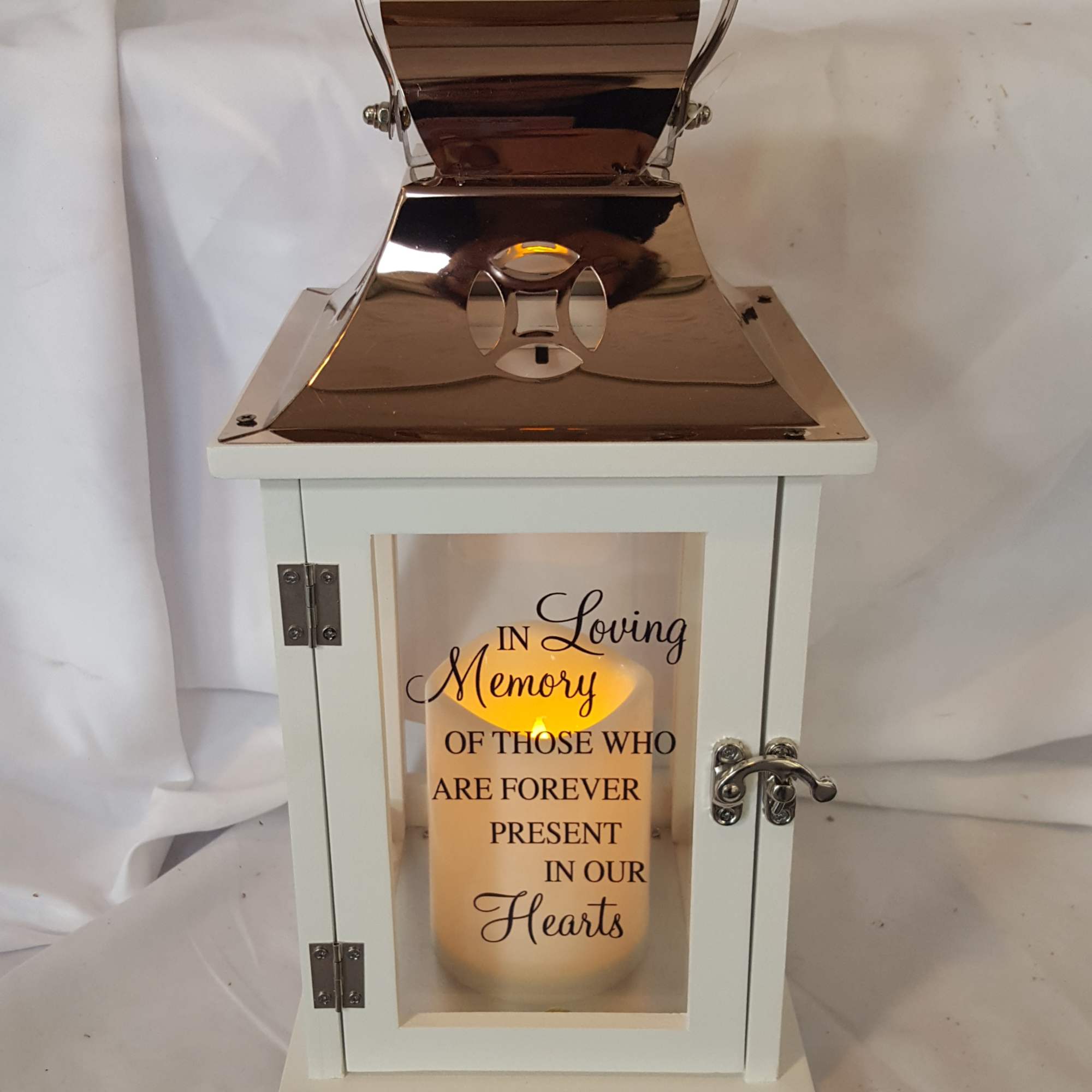 White lantern with a lit memorial candle and copper top