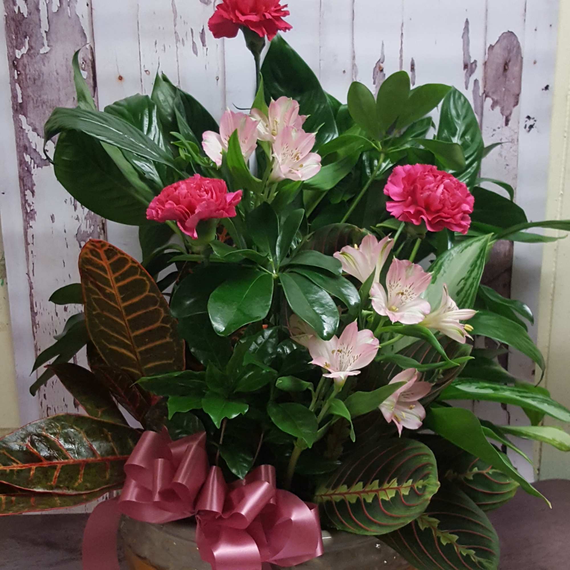 Pink carnations and pale alstroemeria in a low bowl with a ribbon
