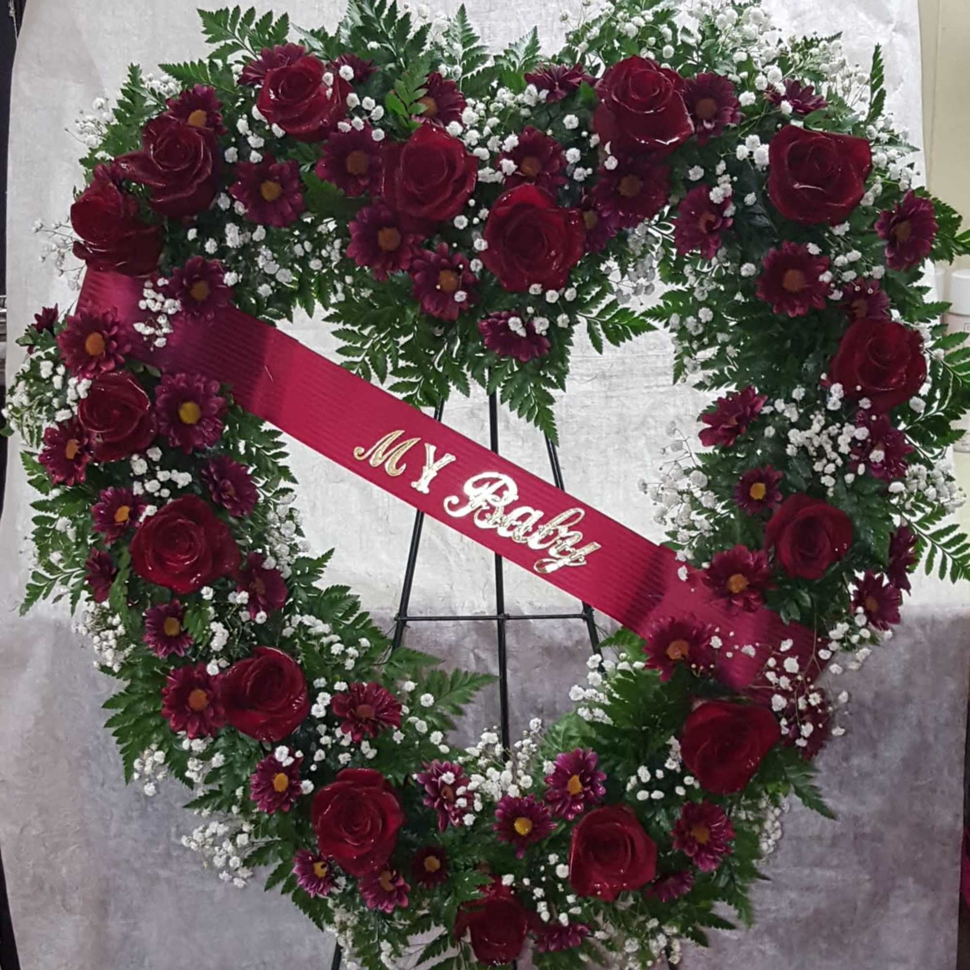 Heart-shaped floral wreath with red roses and a pink ribbon reading "My Baby"