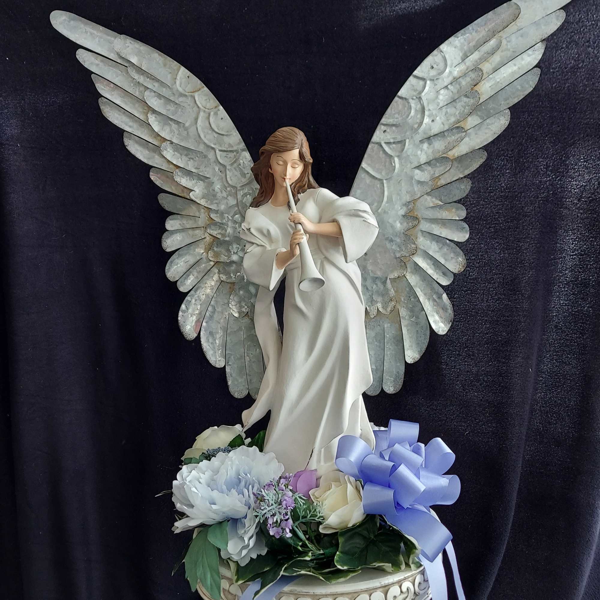 Angel figurine with wings above pastel flowers in a decorative bowl