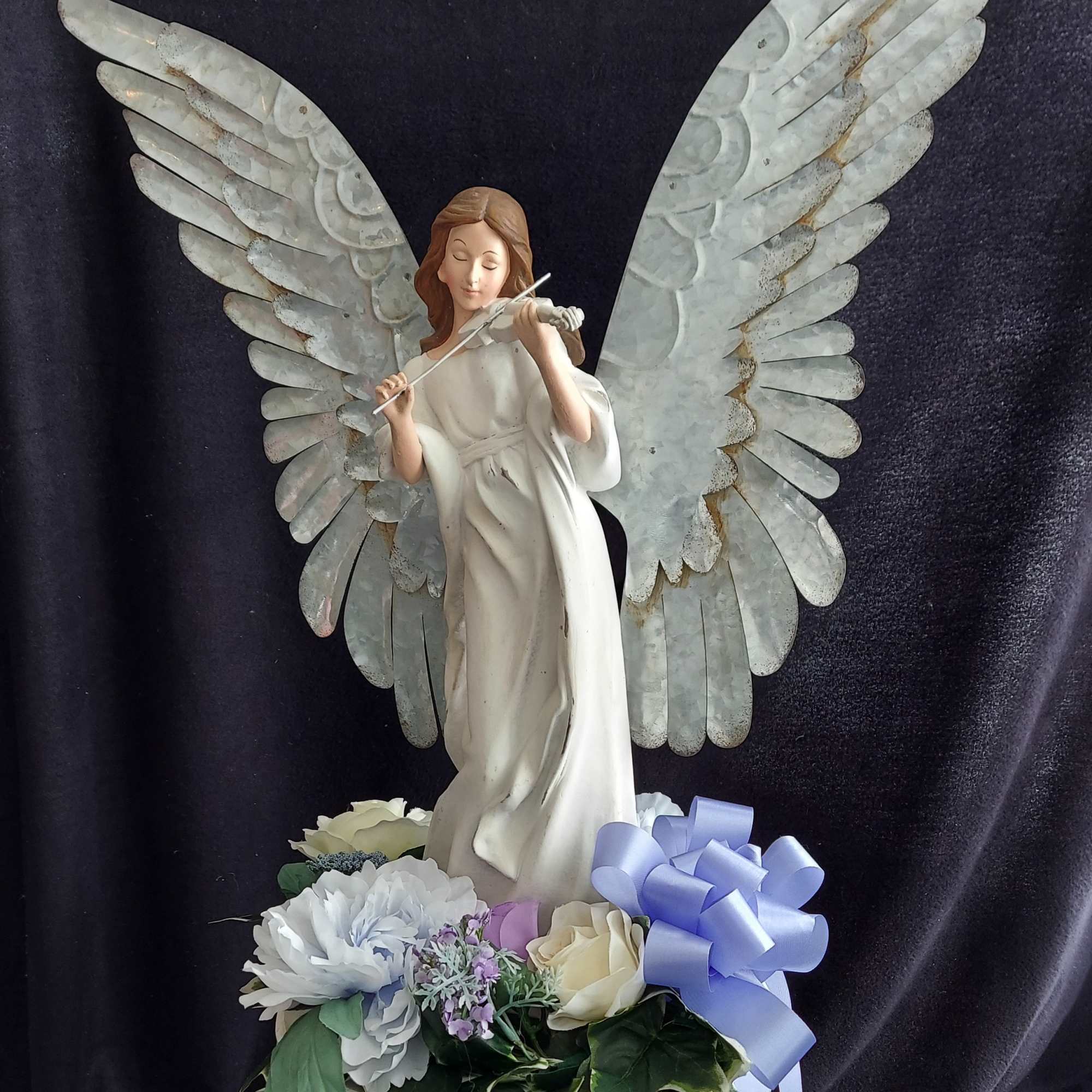 A 25" poly resin angel statue with metal wings is seen playing
