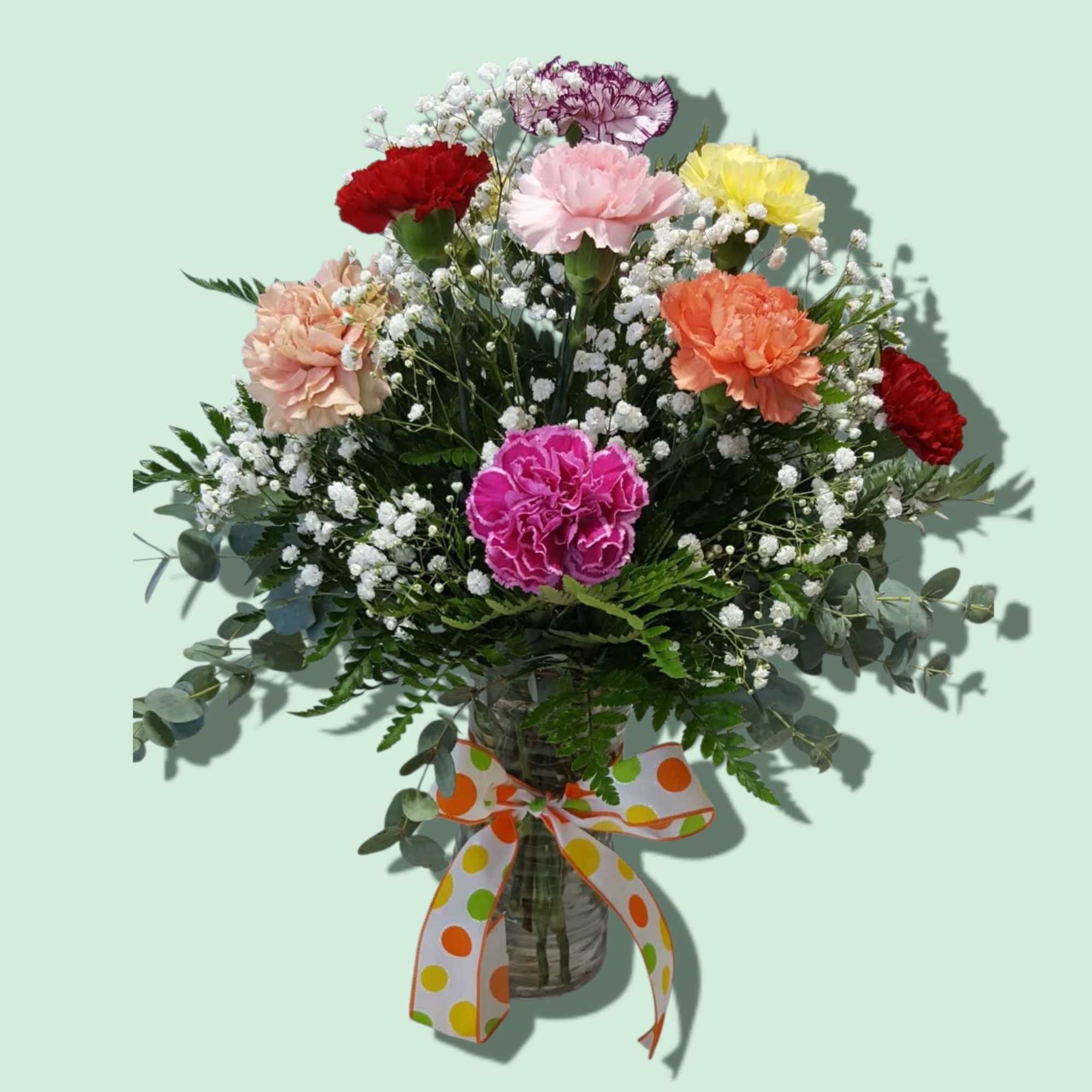 Mixed carnation bouquet in a glass vase with a polka-dot ribbon