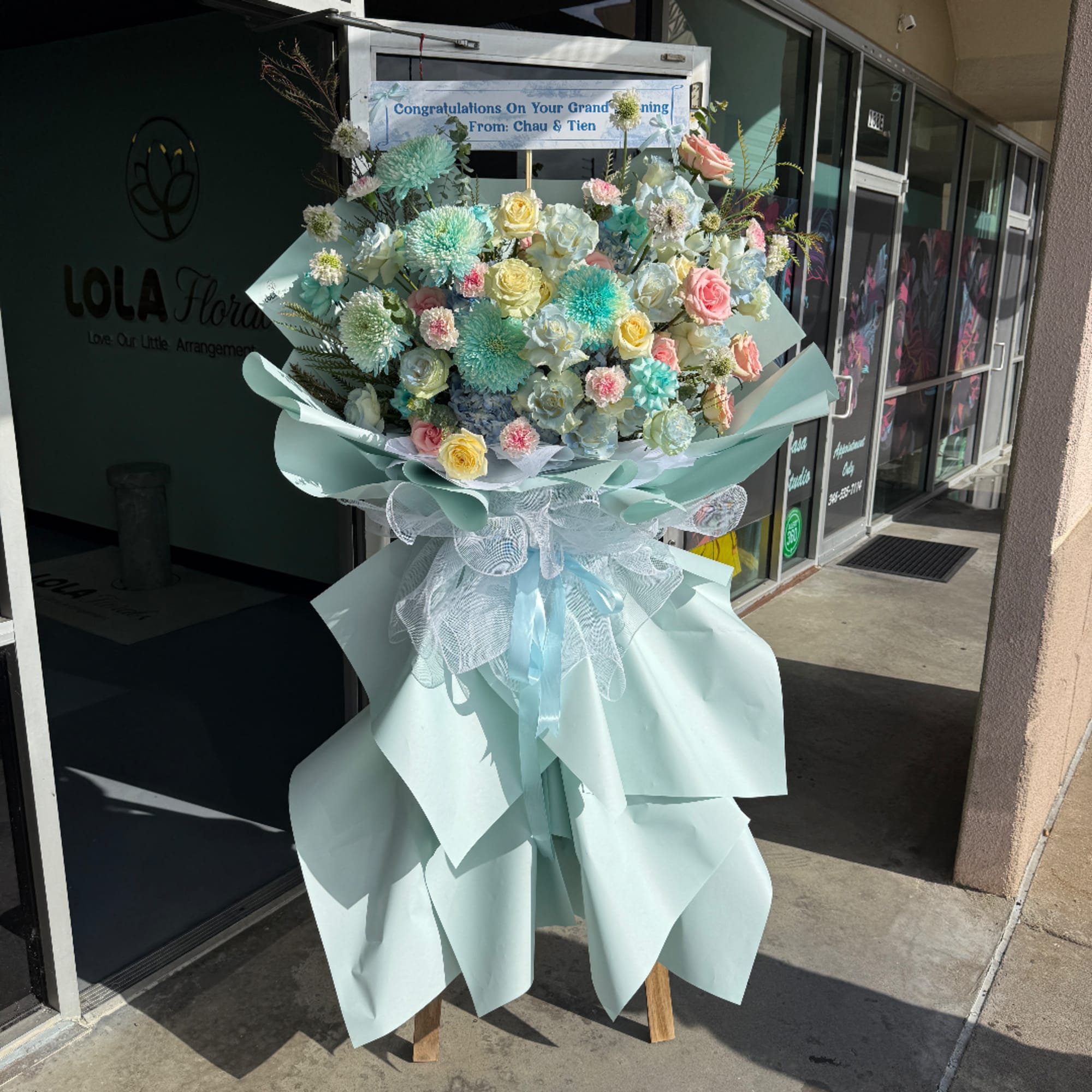 Large pastel flower stand with roses and pompom blooms in mint wrapping