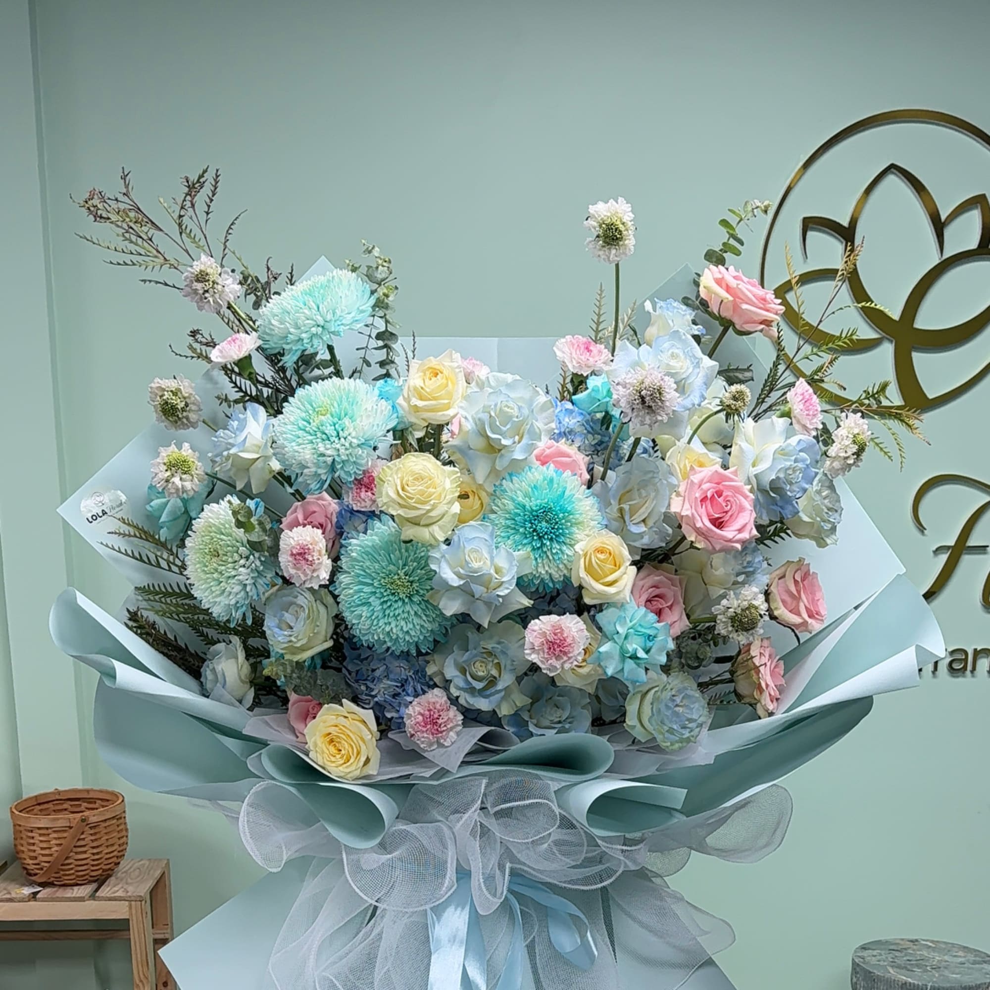 Pastel bouquet of roses, chrysanthemums, and carnations wrapped in blue paper