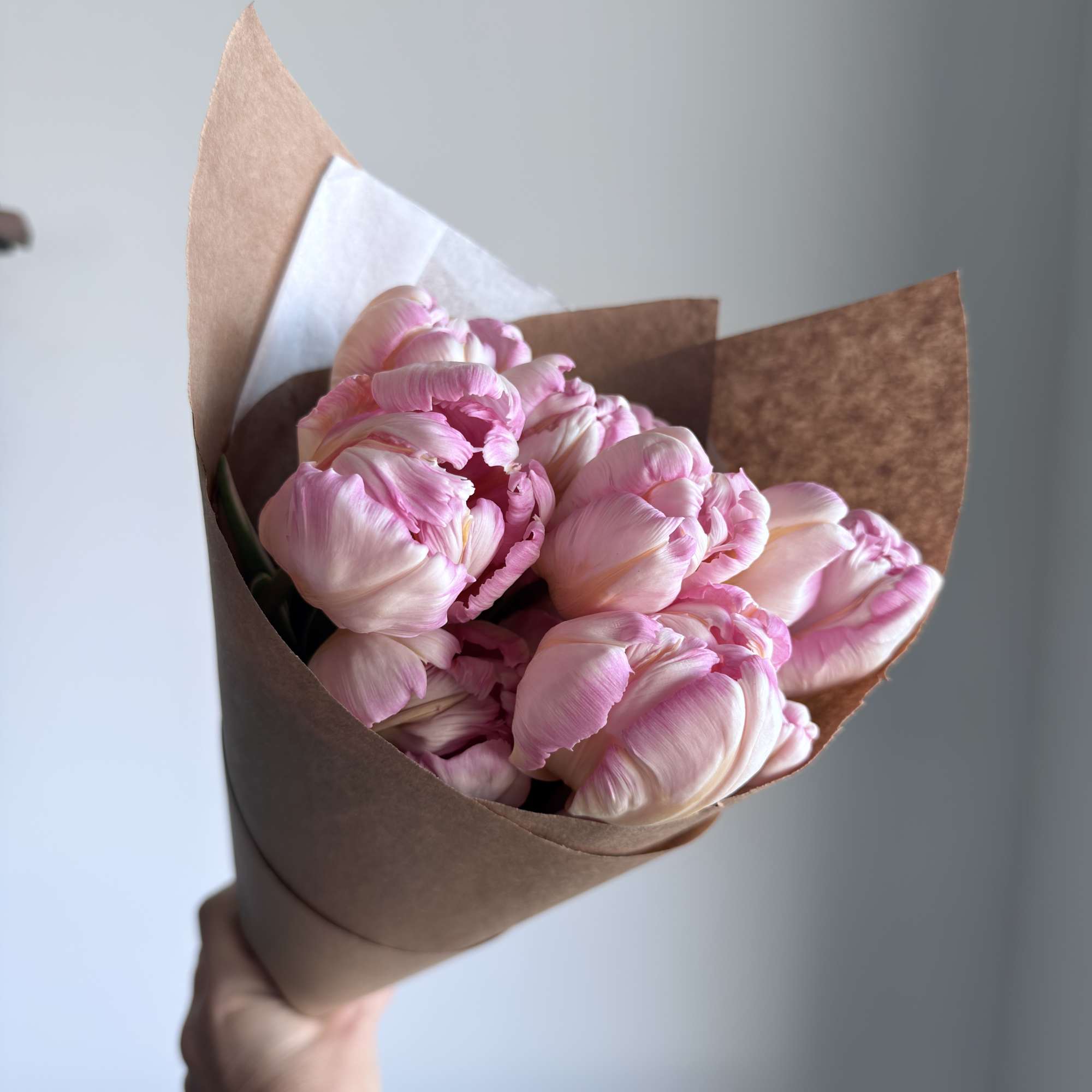 Bouquet of pink tulips wrapped in brown paper