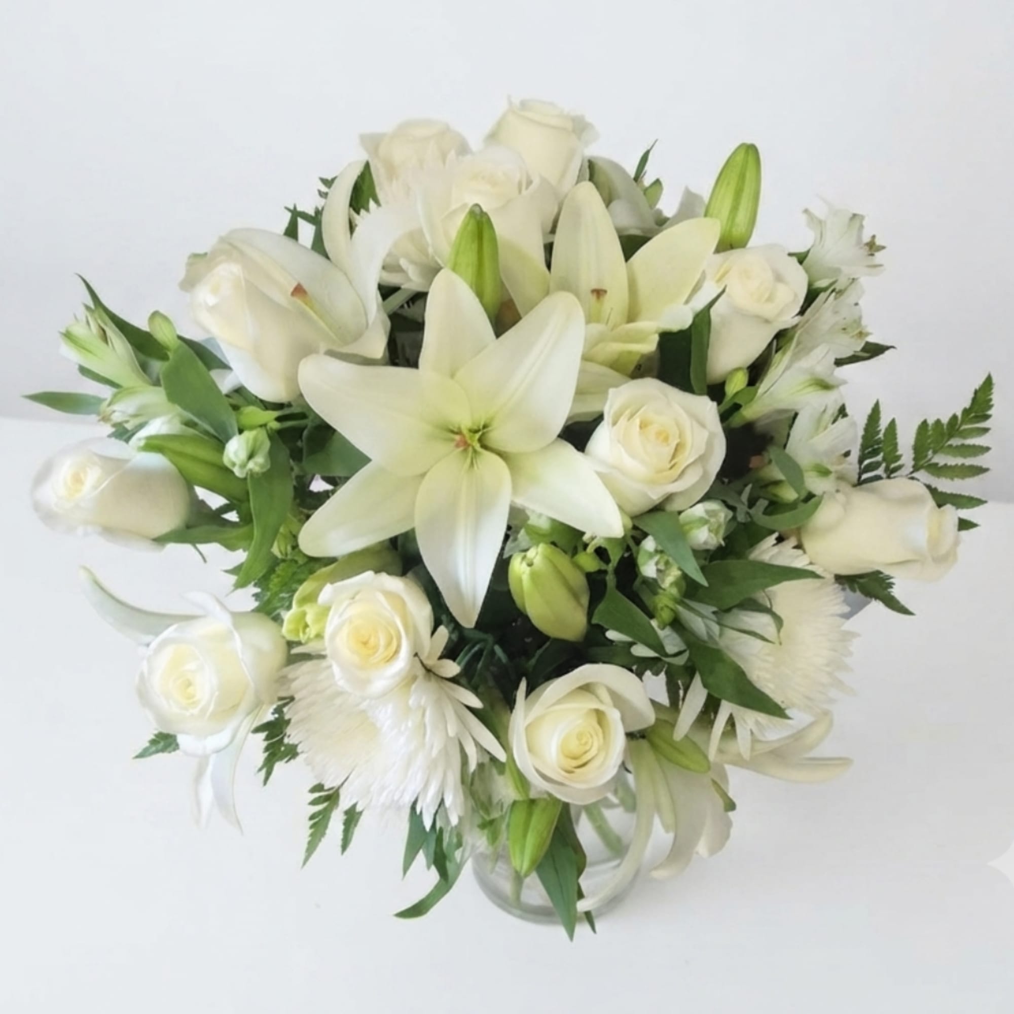 White lilies and roses arranged in a clear glass vase