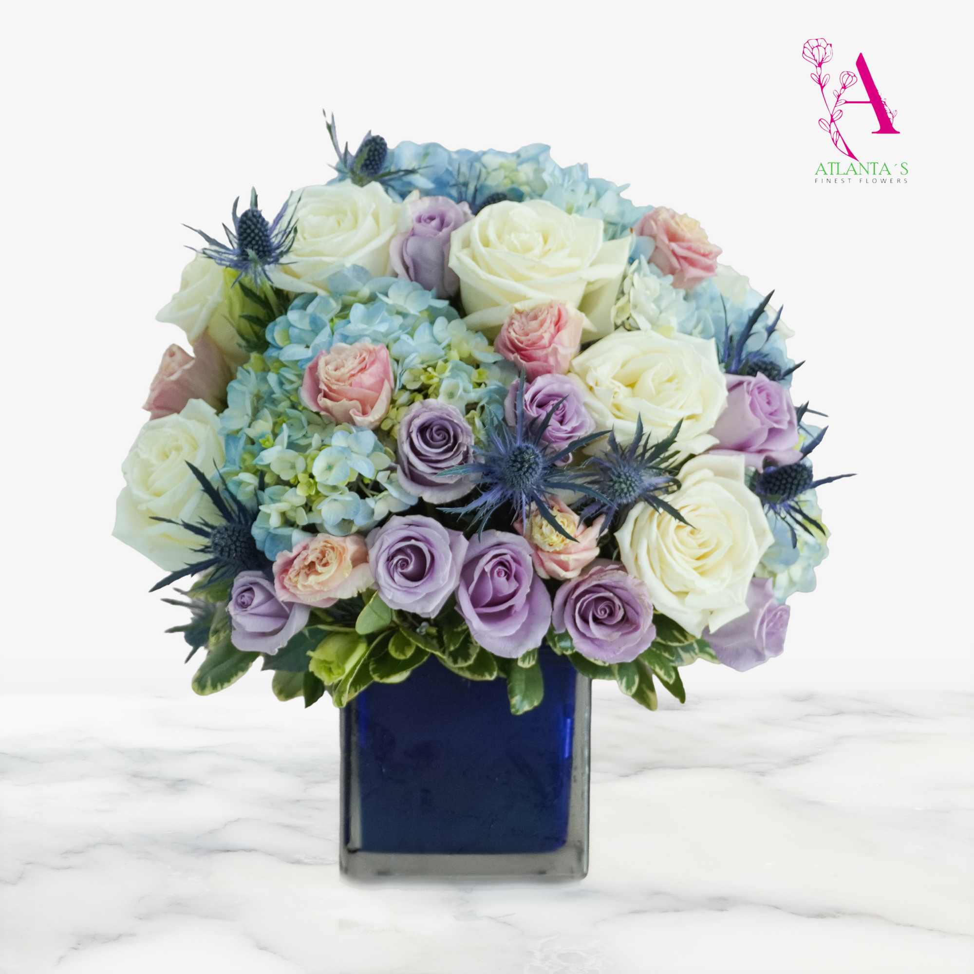 Pastel roses and hydrangeas arranged in a blue square vase