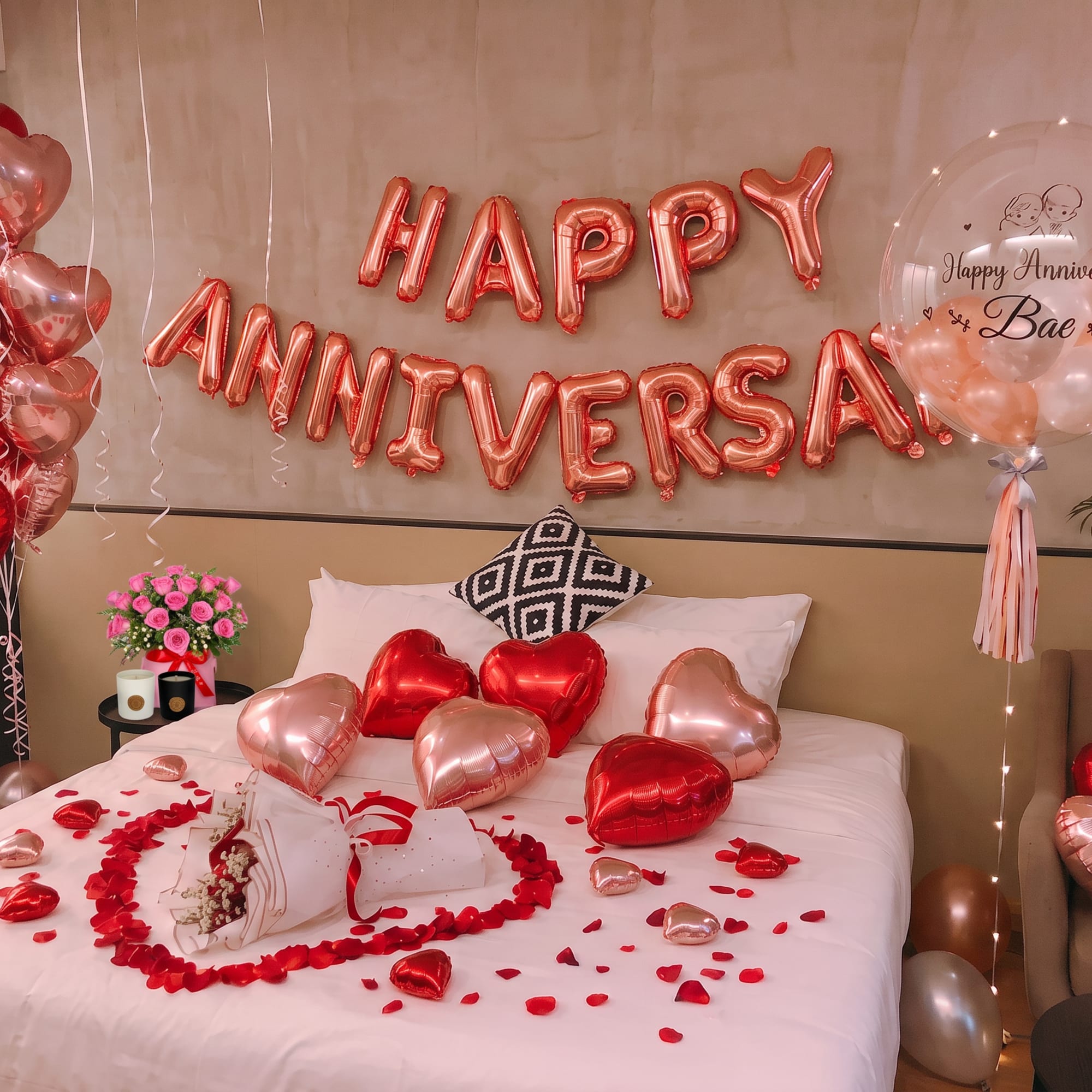 Anniversary room setup with heart balloons, rose petals, and a small pink rose bouquet