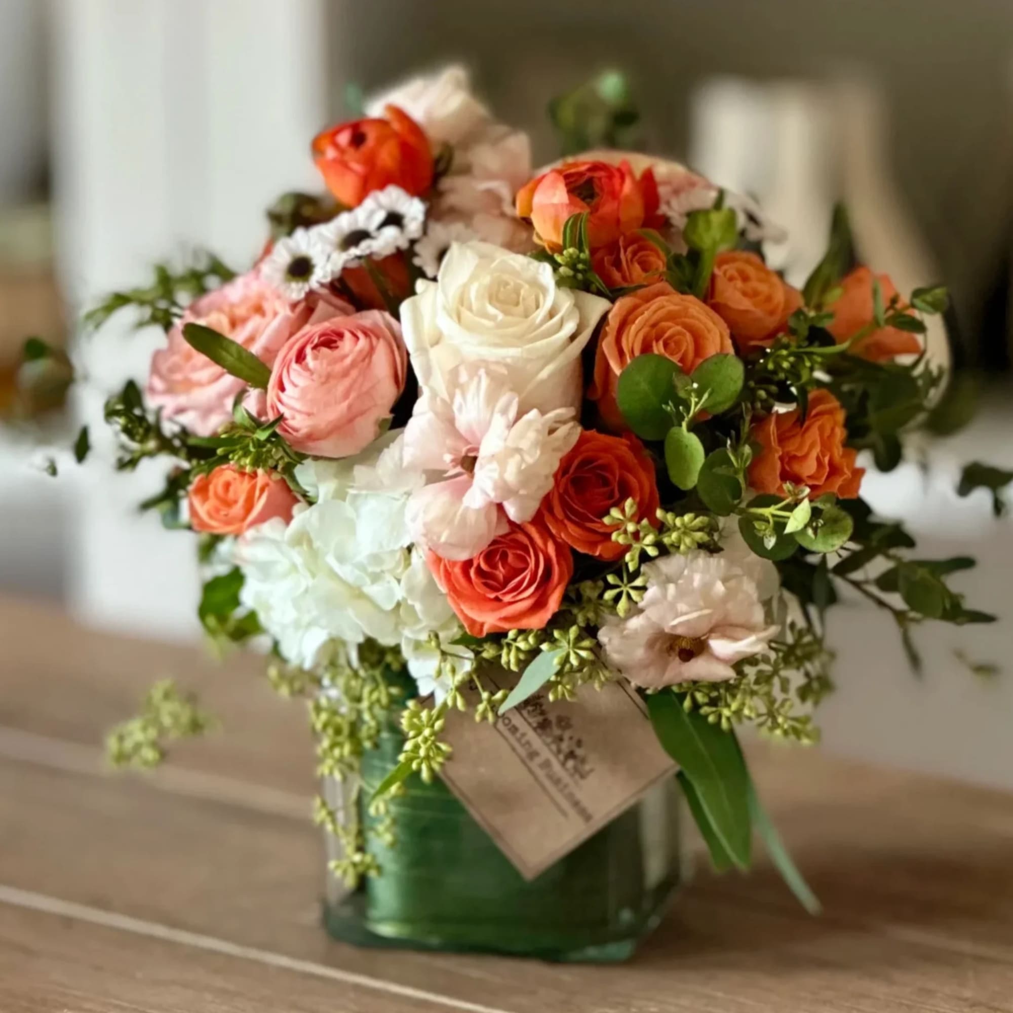 Bouquet of pink, white, and orange roses in a green glass vase