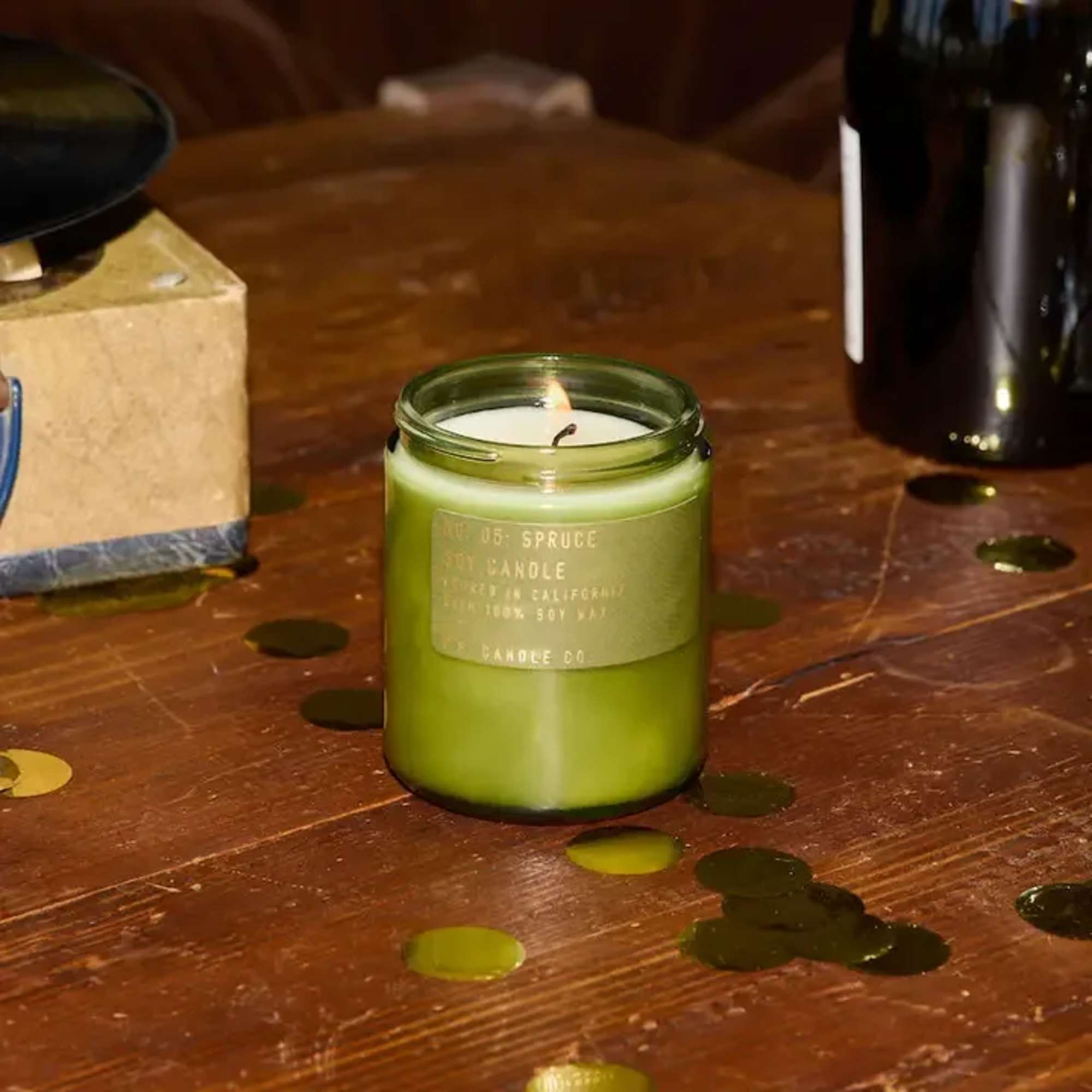 Green candle in a glass jar on a wooden table