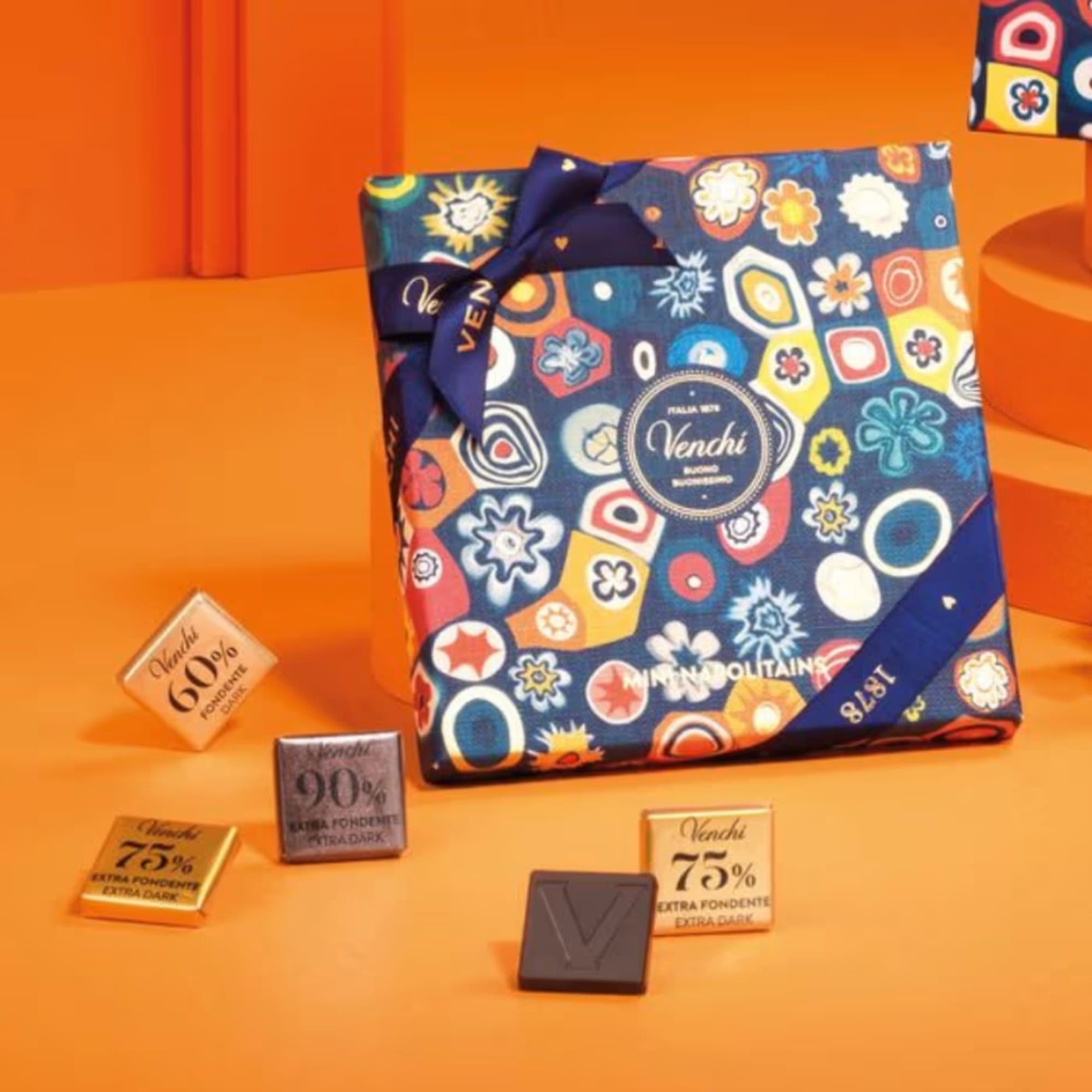 Gift box of assorted chocolates tied with a ribbon on an orange background