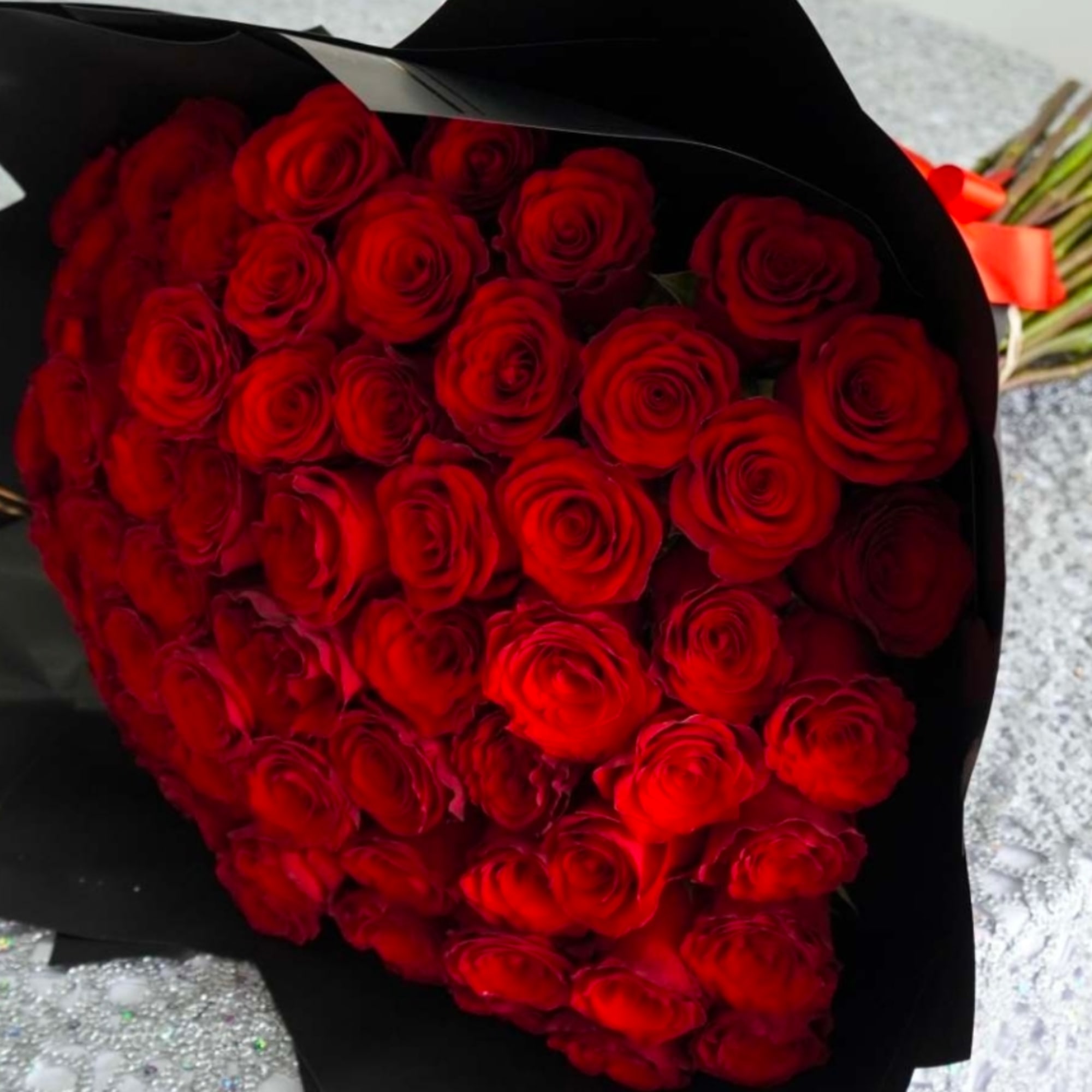 Heart-shaped bouquet of red roses wrapped in black paper