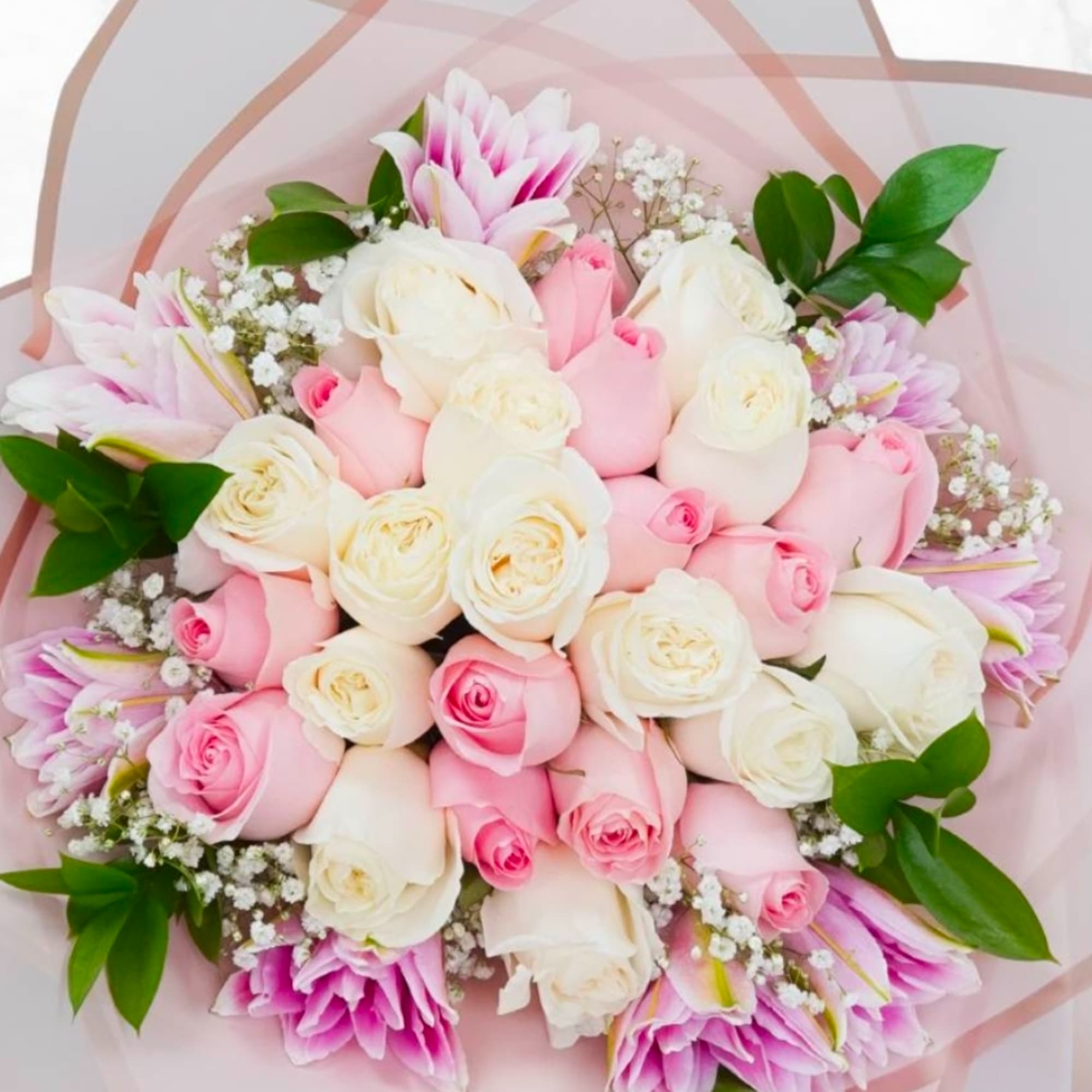 Bouquet of pink and white roses with pink lilies wrapped in pale pink paper