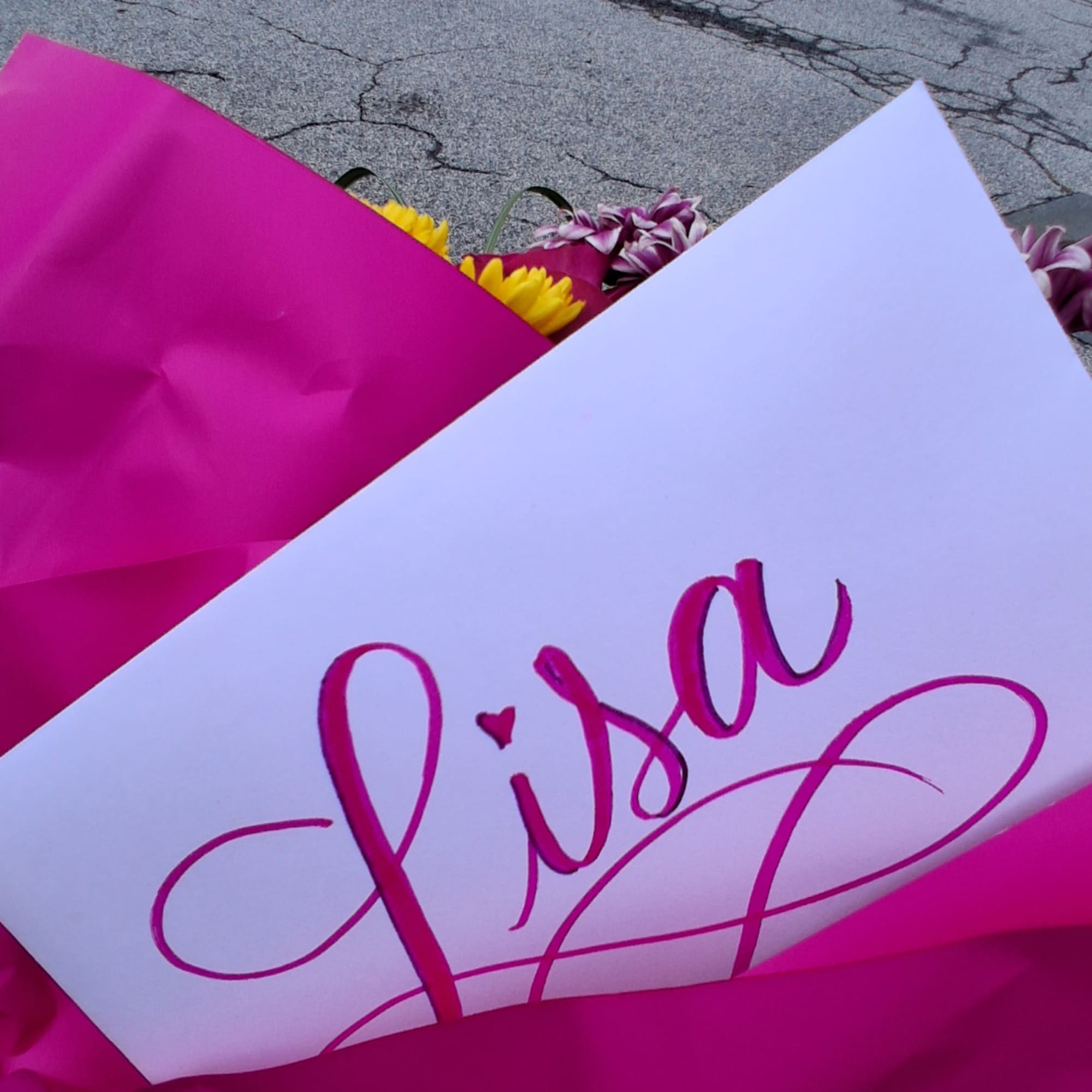 Pink-wrapped bouquet with yellow and purple flowers and a card labeled "Lisa"