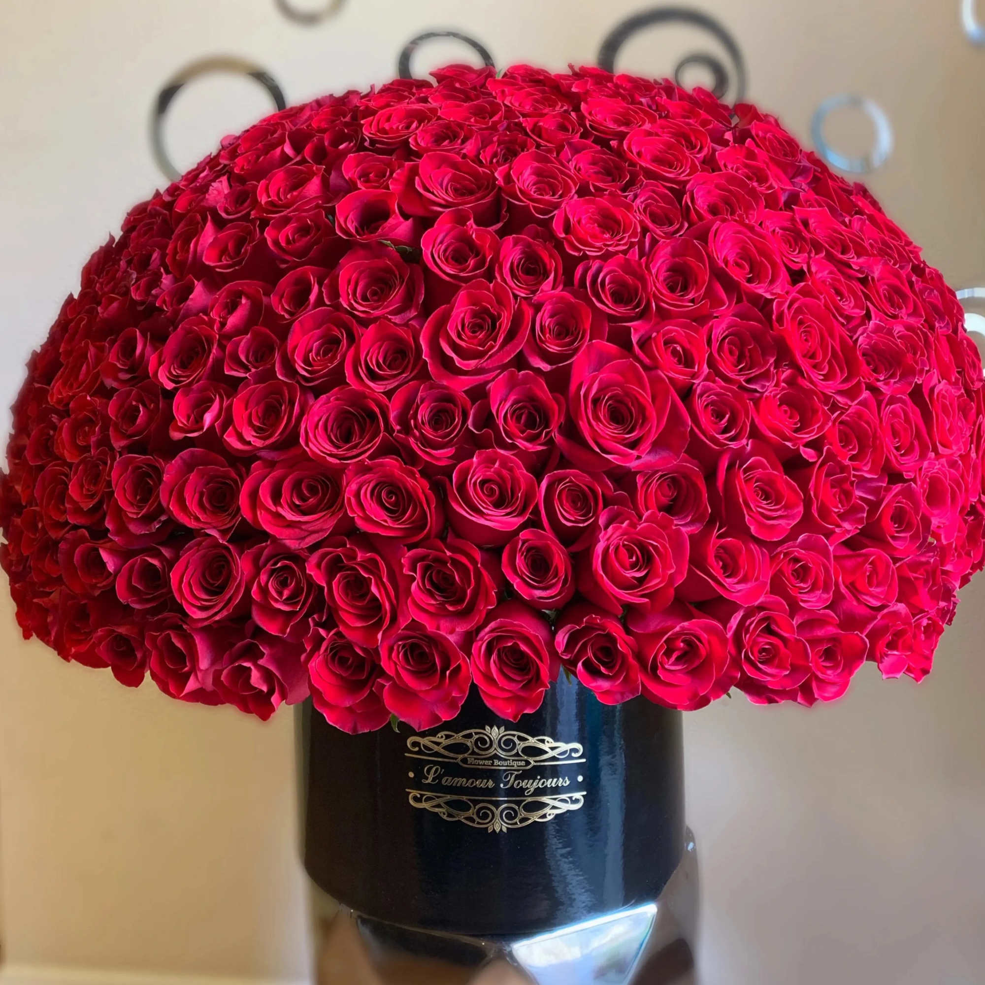 Large dome of tightly packed red roses arranged in a round black hatbox container