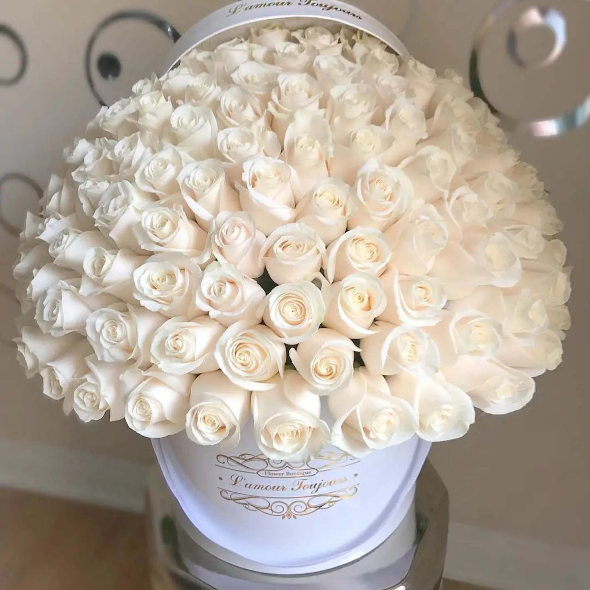 Round hat box filled with tightly packed ivory roses in a dome shape