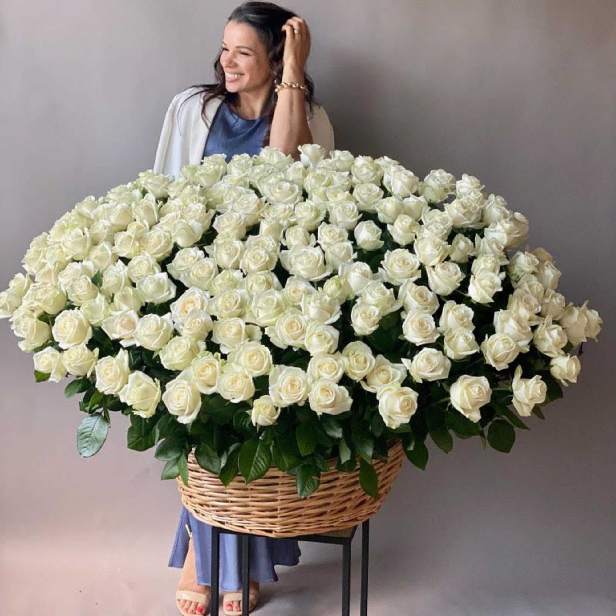Large basket arrangement of white roses held by a woman