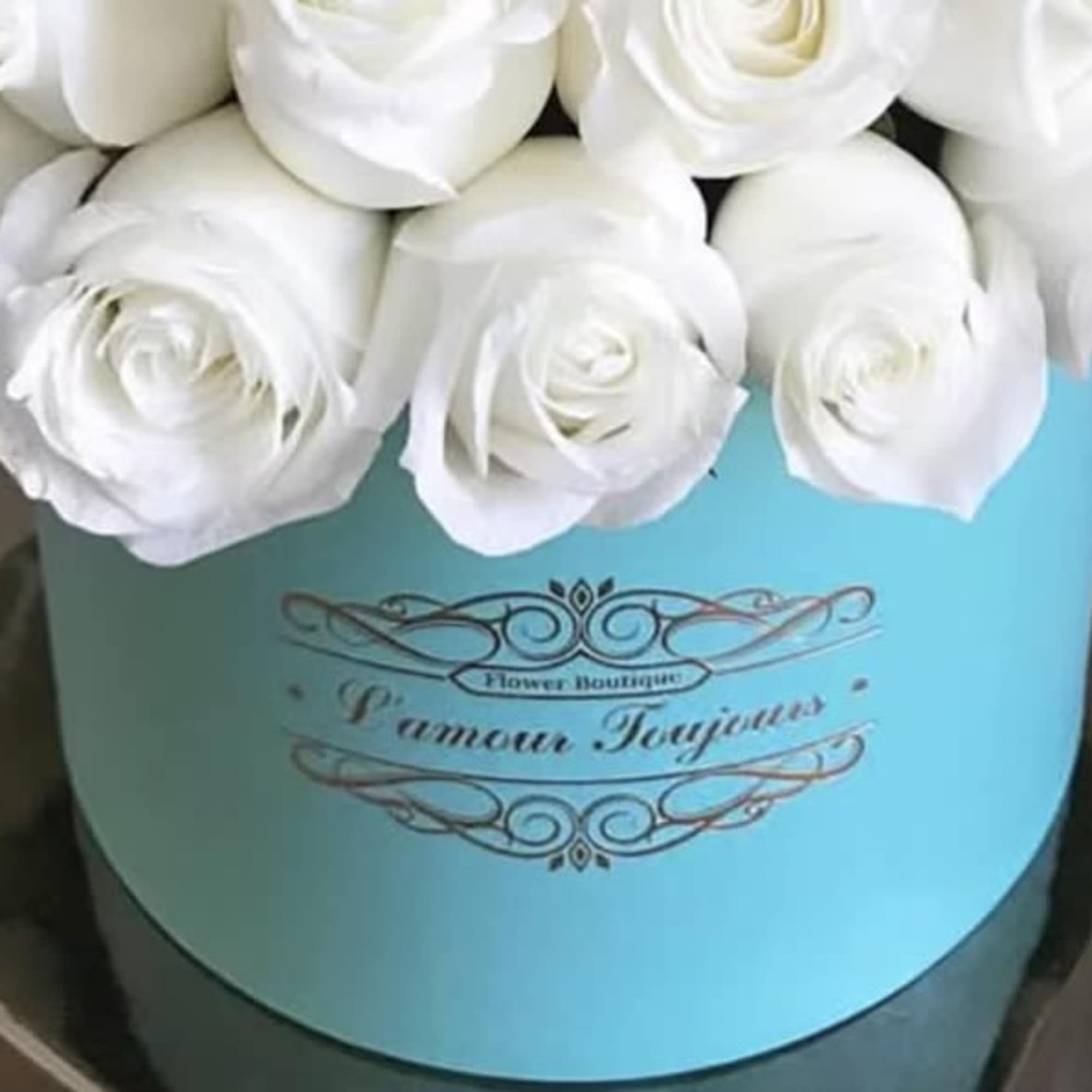 White roses arranged in a turquoise hat box