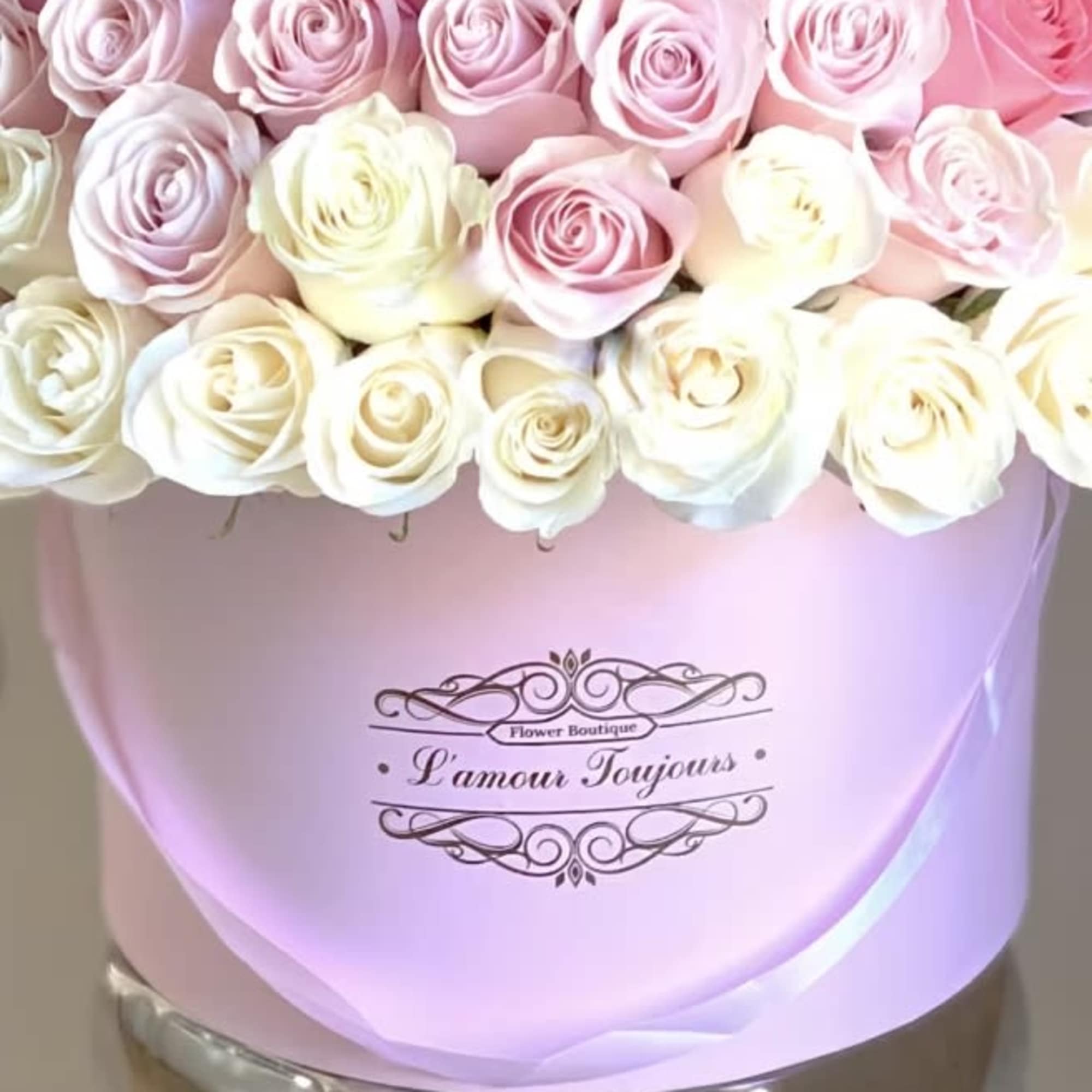 Round pink hatbox filled with rows of pale pink and white roses