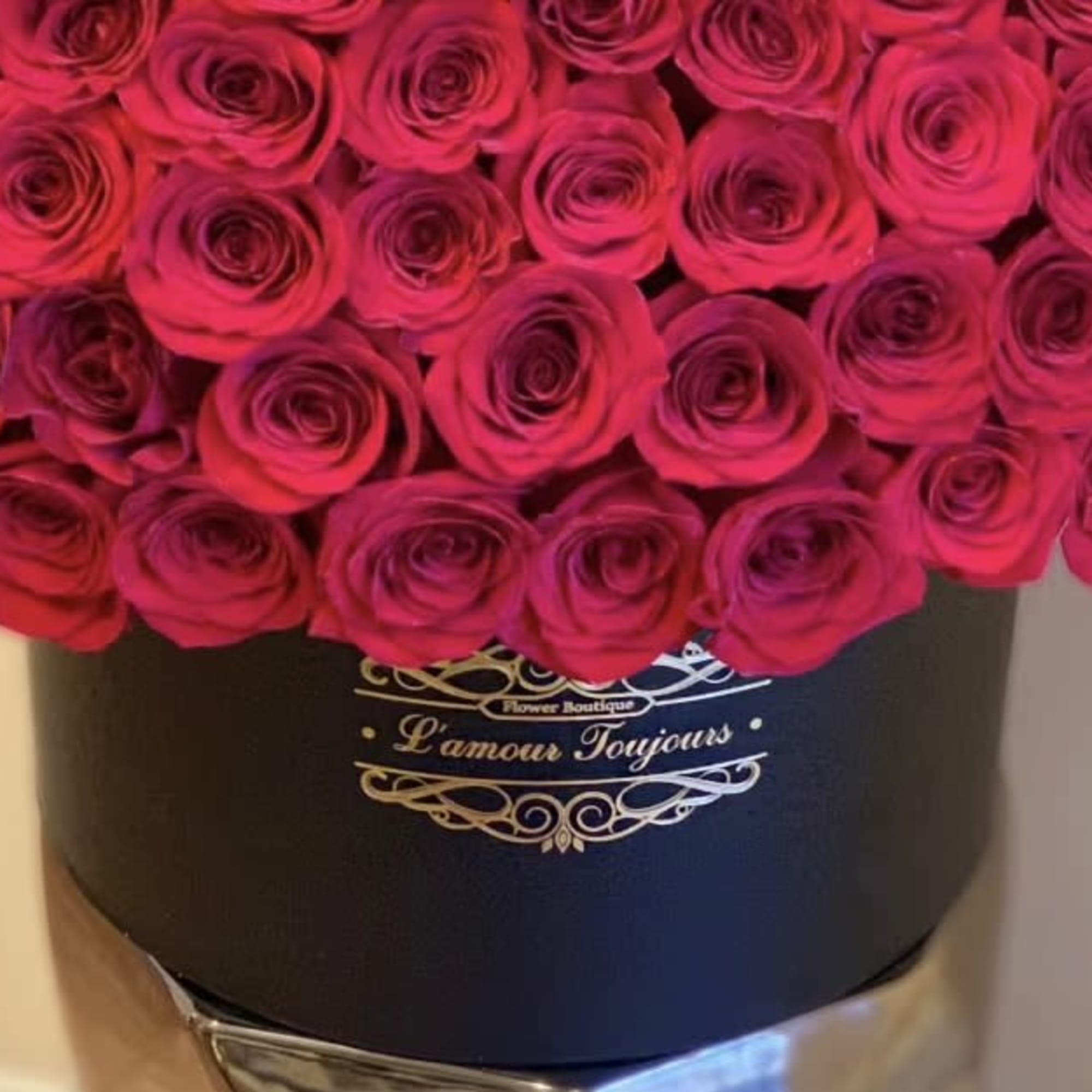 Round box of hot pink roses arranged tightly in a black hatbox container