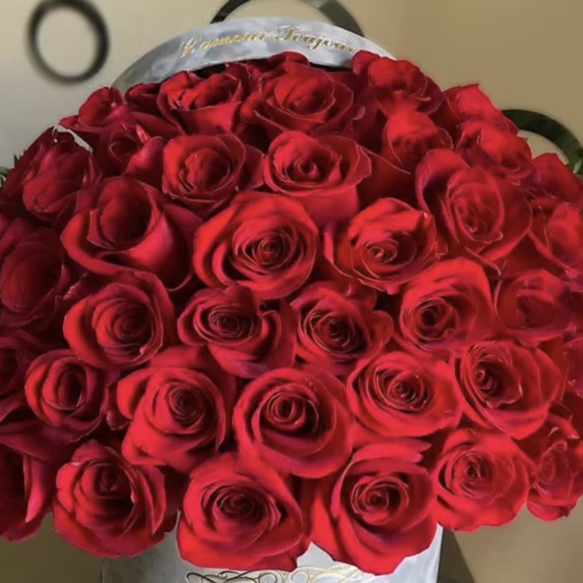 Large dome-style arrangement of red roses in a light-colored hatbox container
