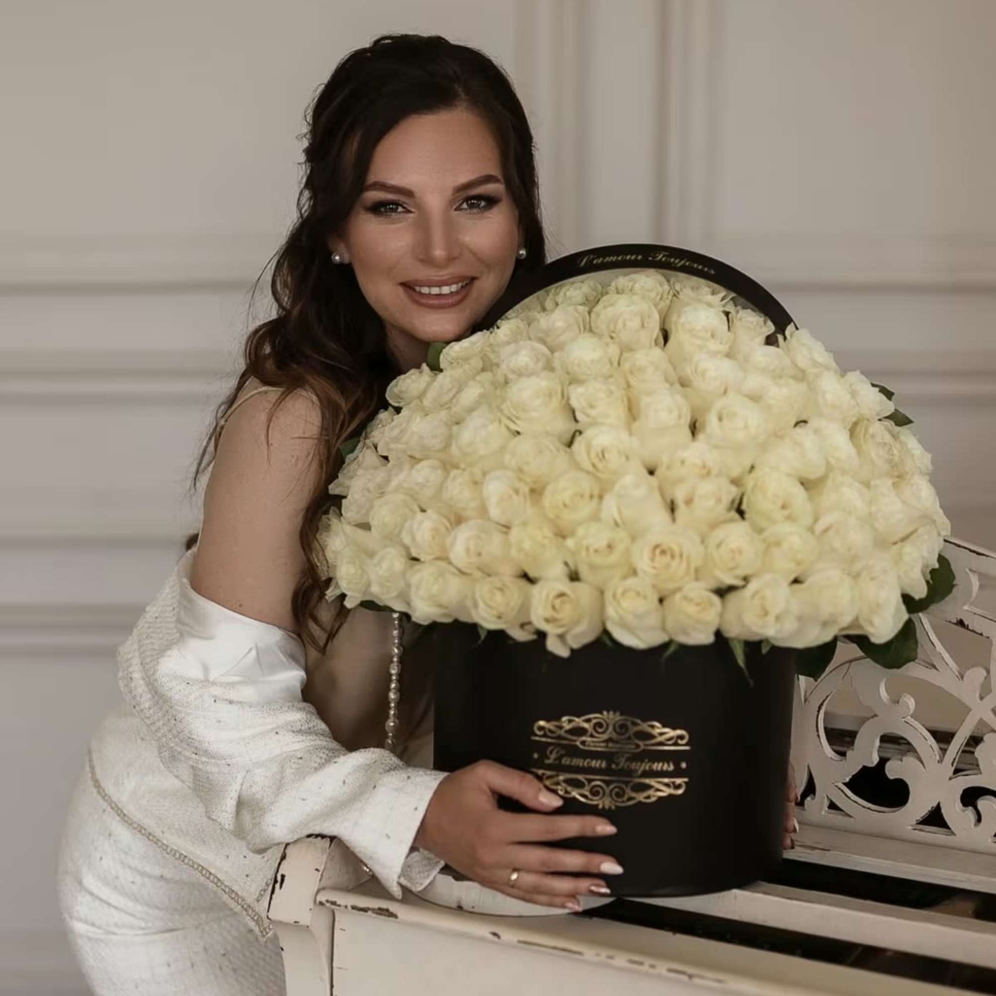 Woman holding a large black hatbox filled with cream roses