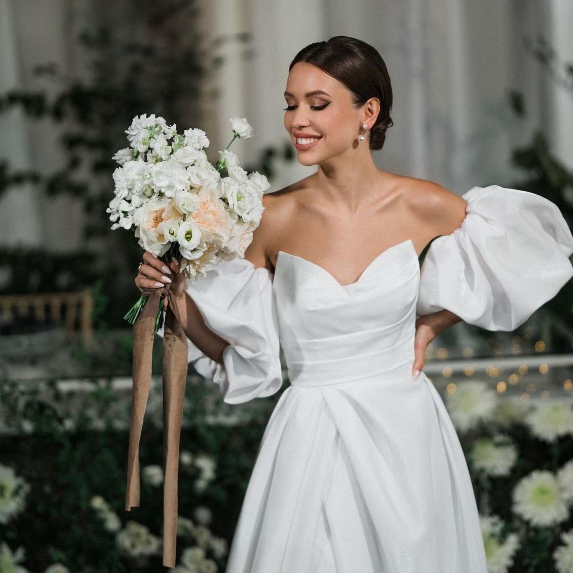 Bride holding a white wedding bouquet with long ribbon streamers