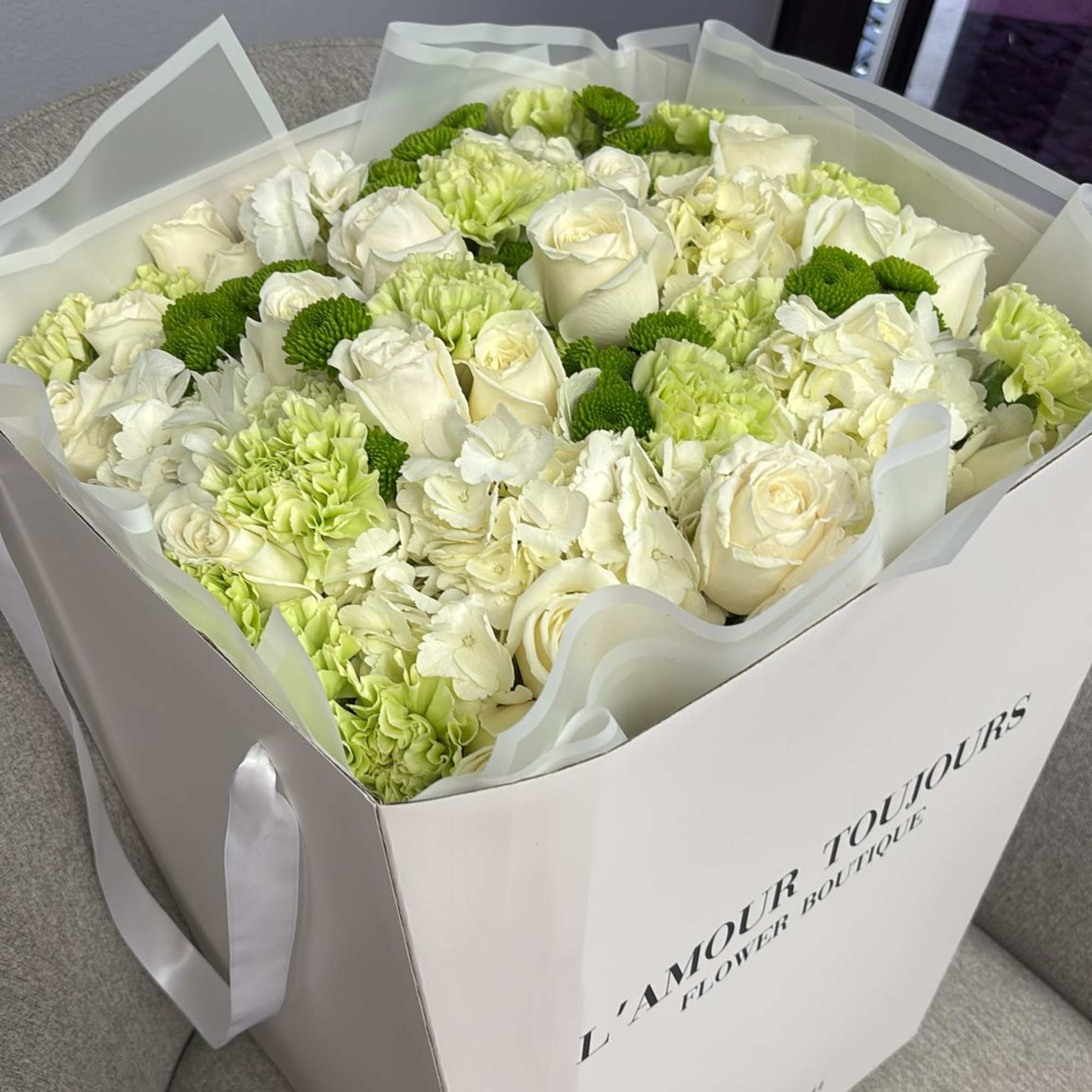 White roses and green carnations in a white gift box