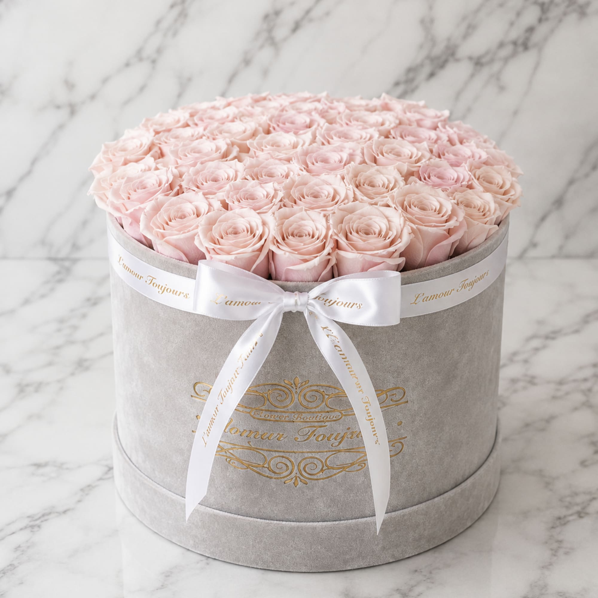 Round box of pale pink roses tied with a white ribbon