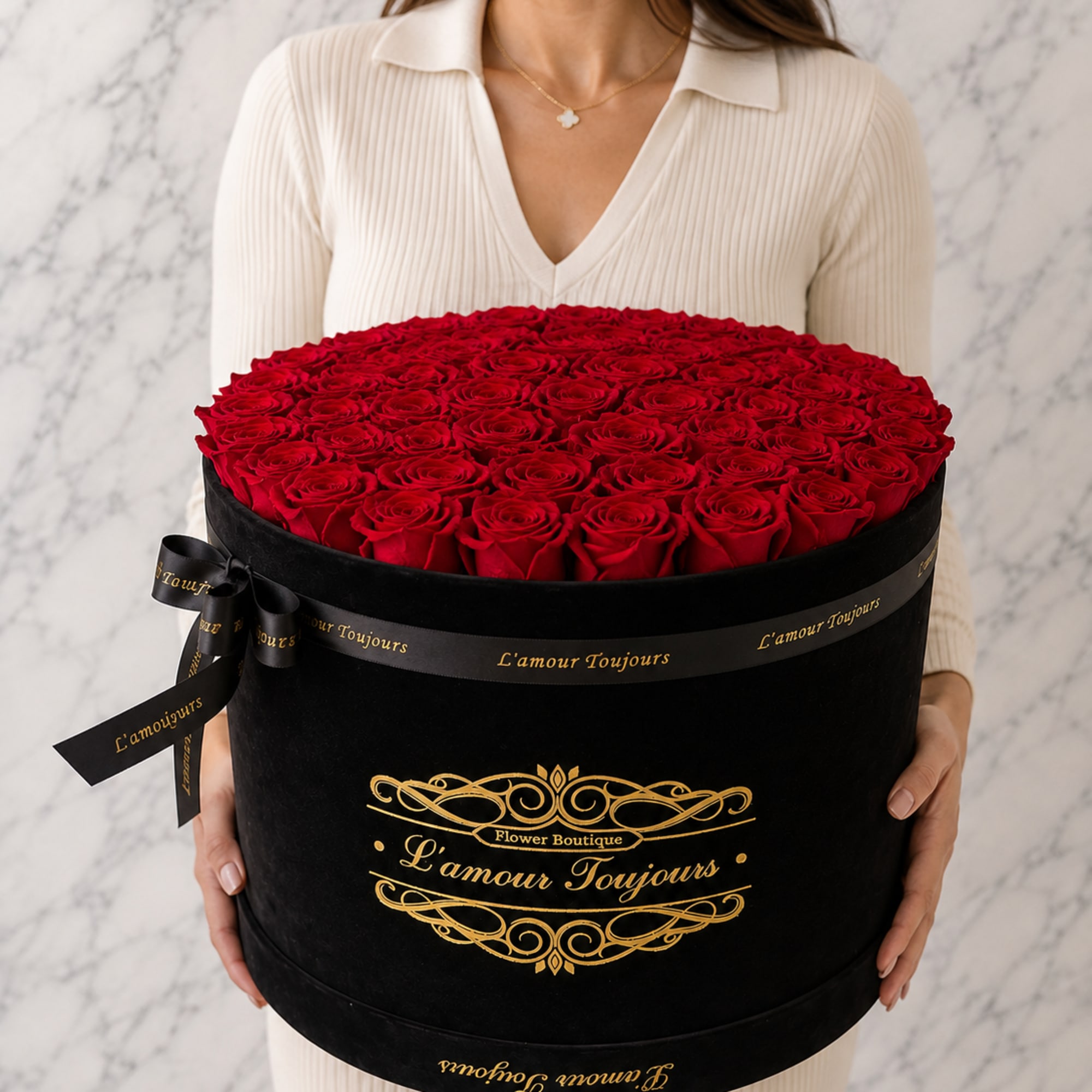 Woman holding a large round box of red roses with a black ribbon
