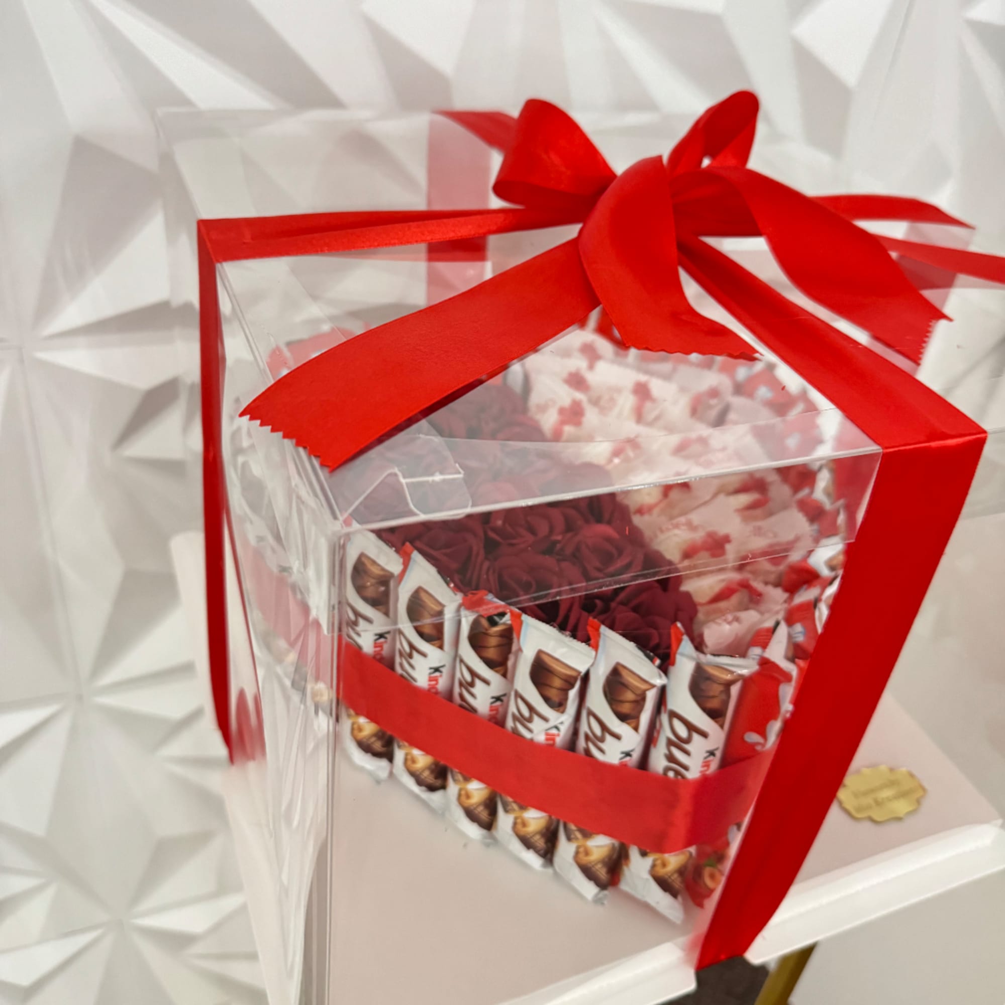 Gift box with red ribbon, roses, and chocolate bars