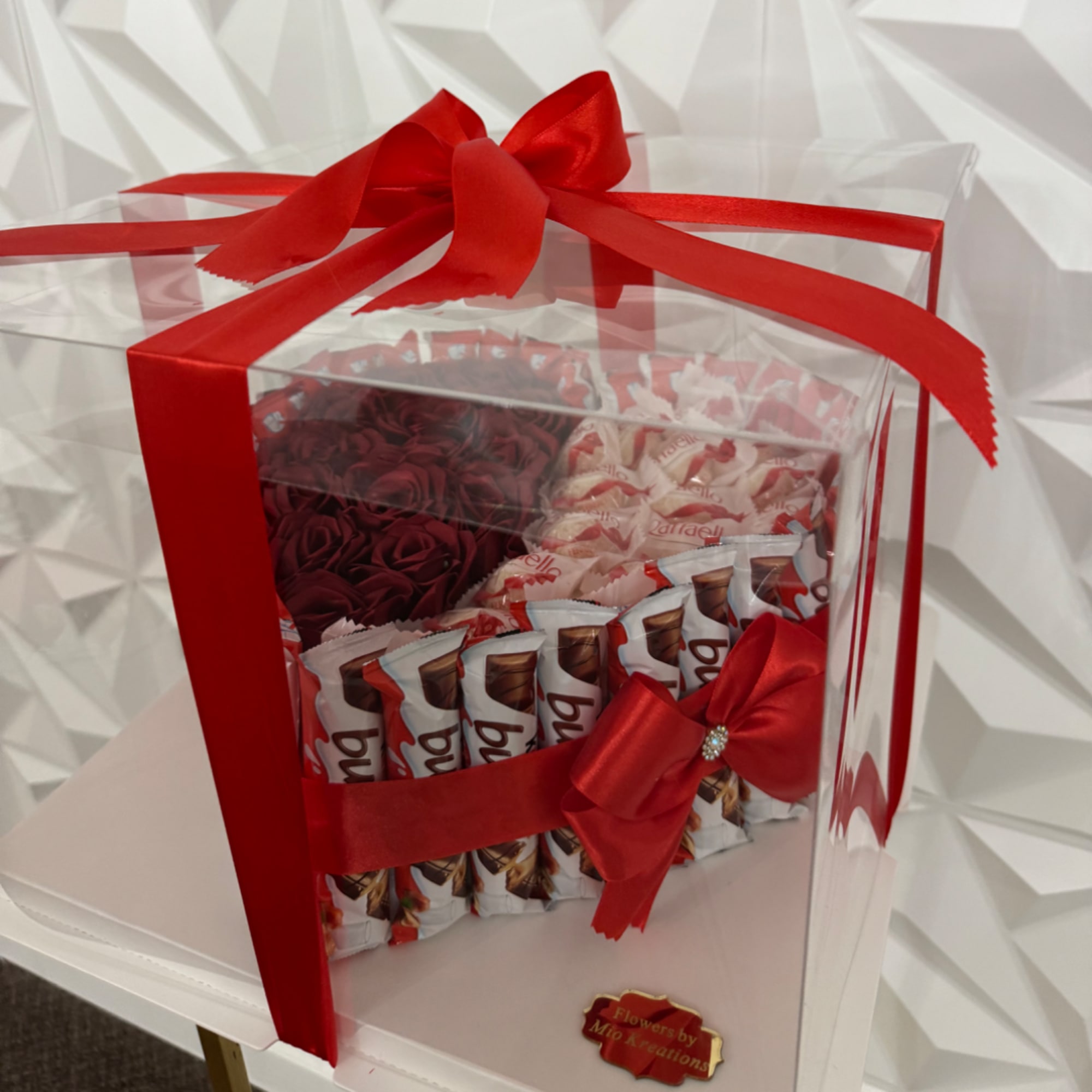 Gift box with red ribbon, faux roses, and chocolate bars