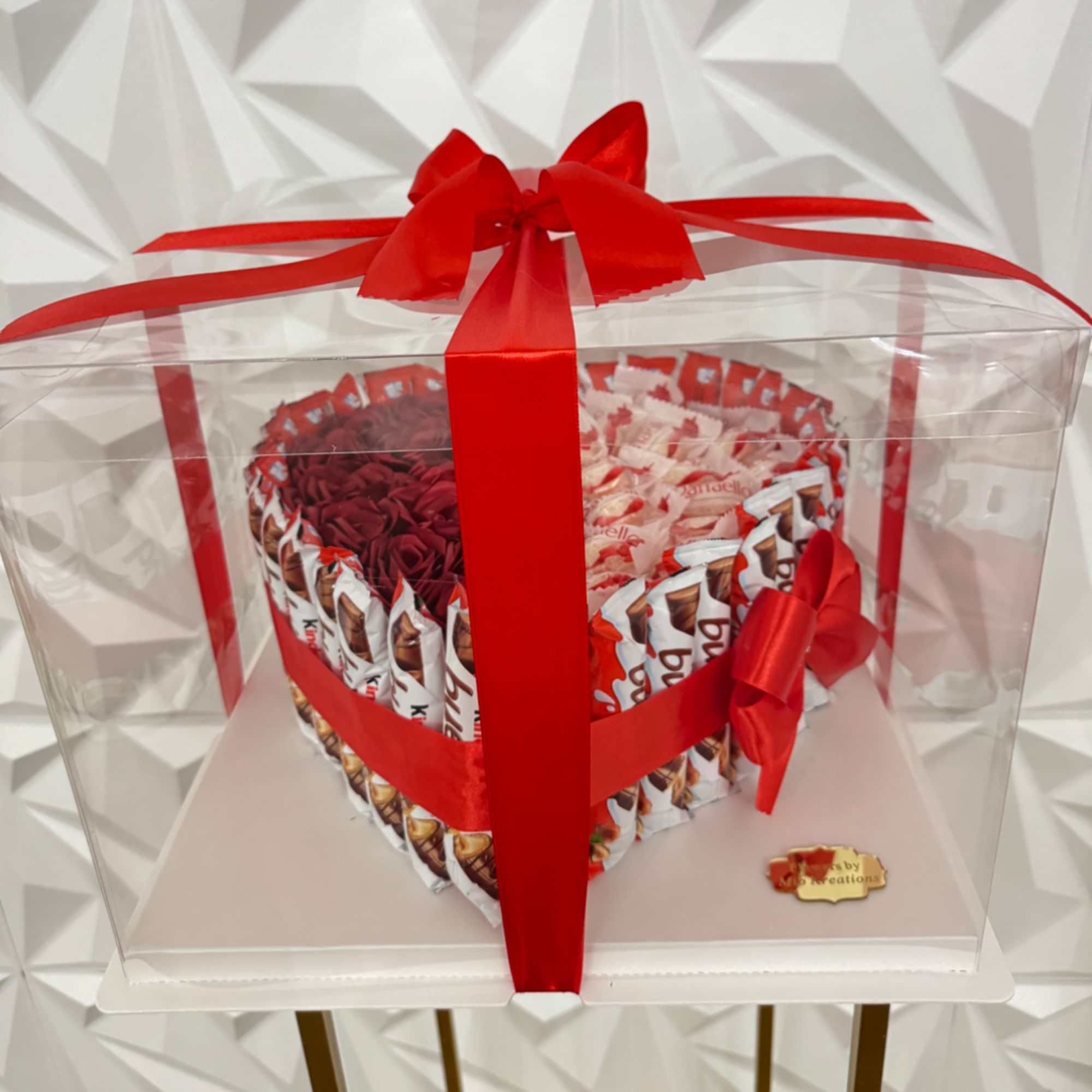 Heart-shaped gift box filled with red and pink chocolates, wrapped with a red ribbon