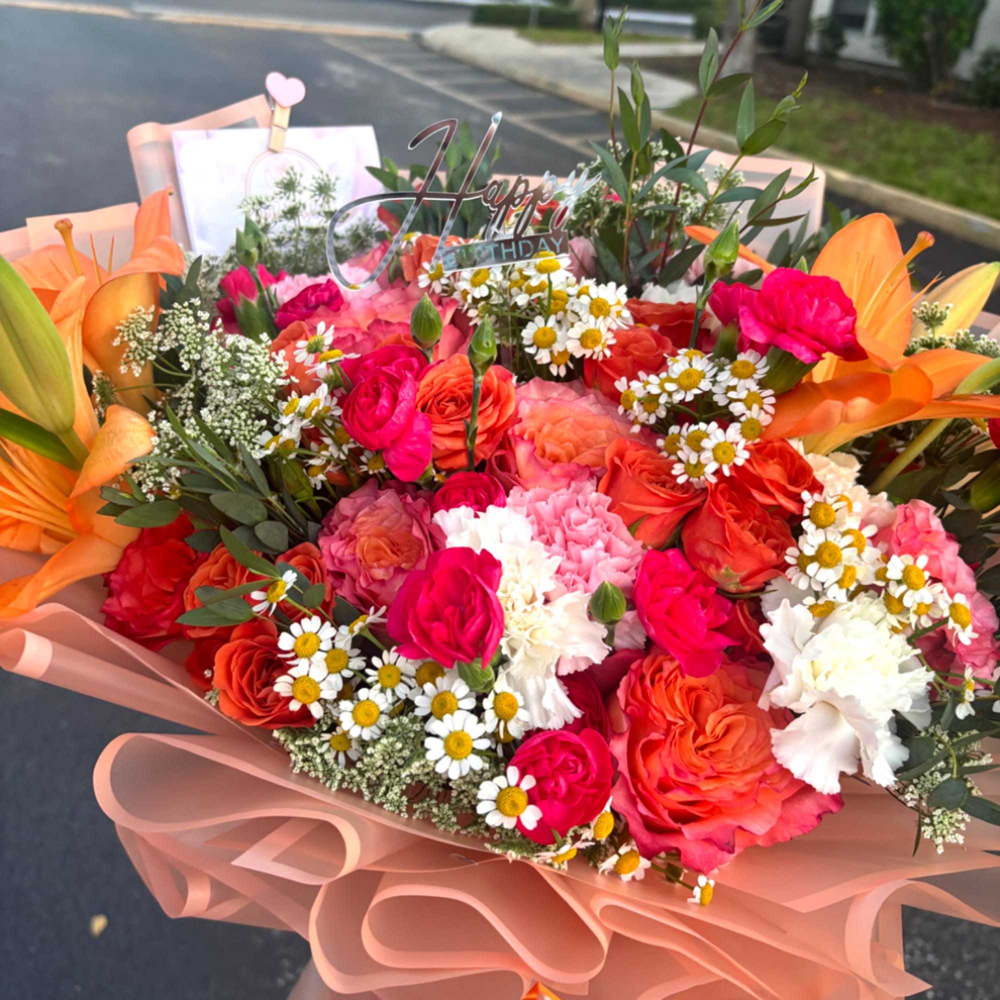 Large bouquet of orange, pink, and white flowers with a birthday topper