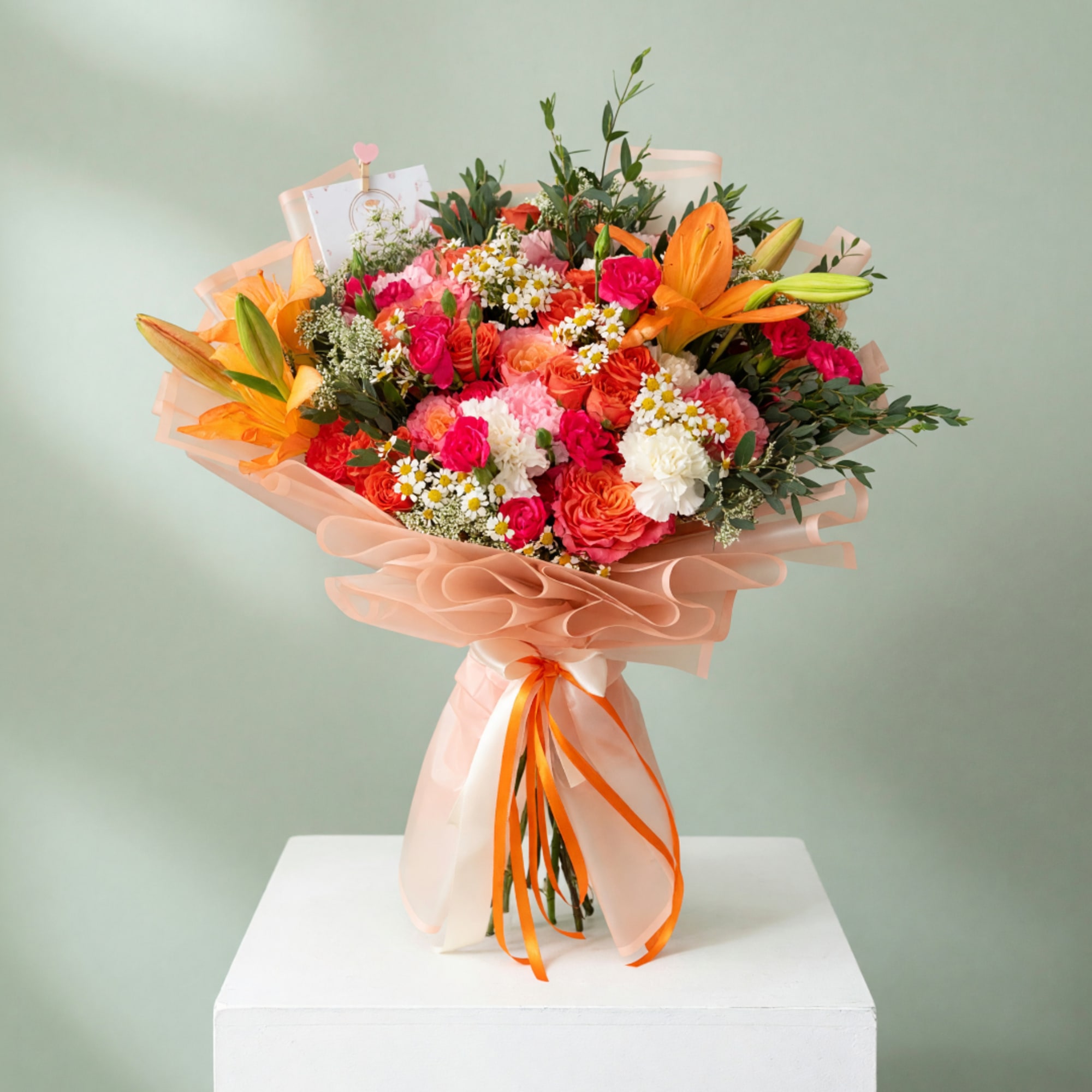 Large bouquet of orange lilies, pink roses, and white daisies wrapped in peach paper
