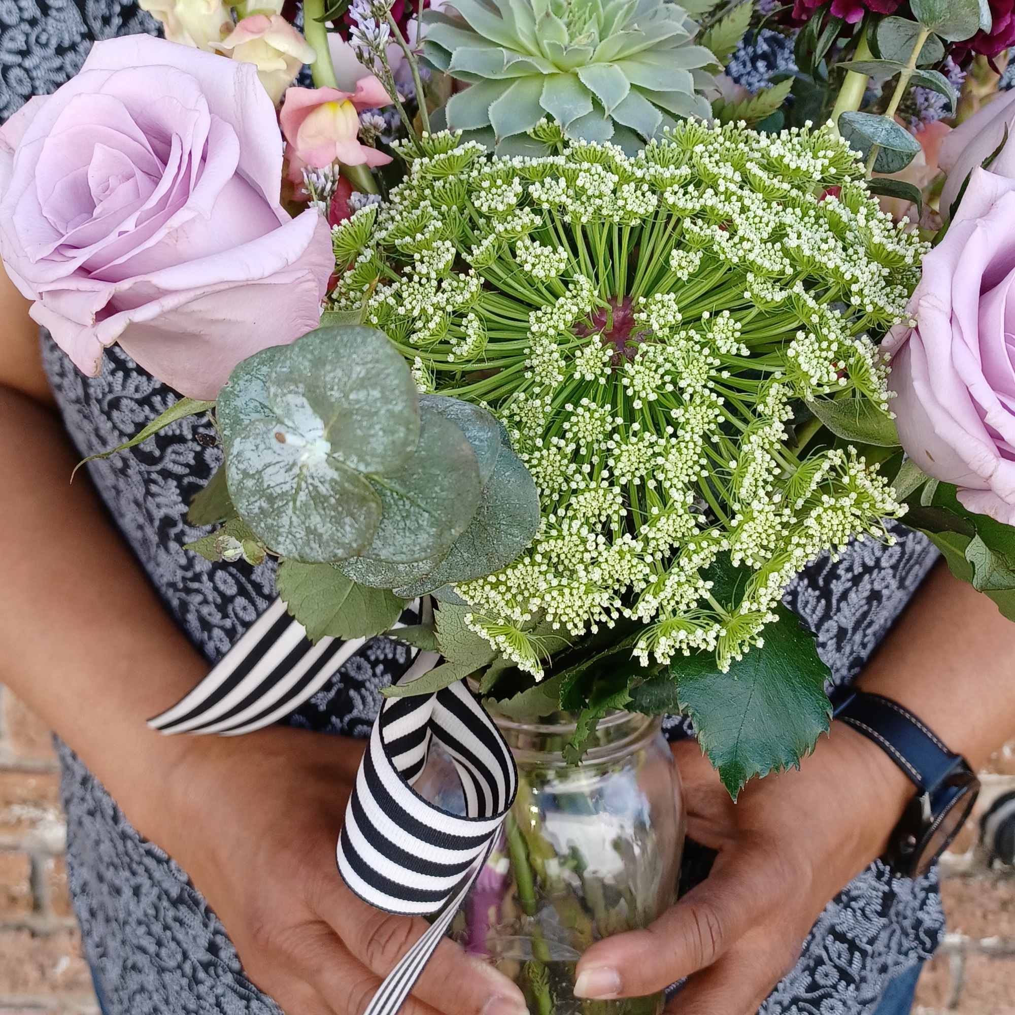 Bouquet of lavender roses and mixed blooms in a glass jar