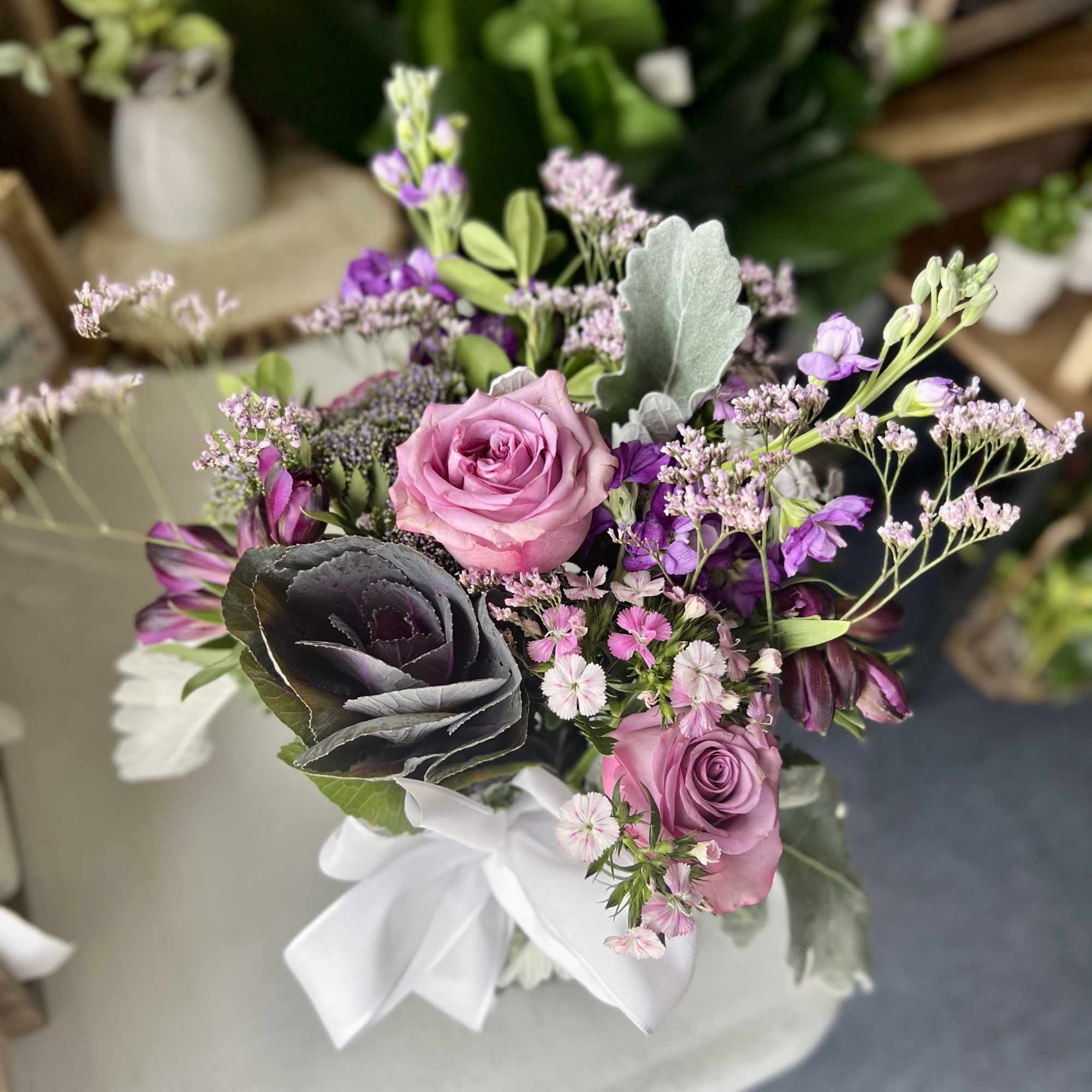 Pink and purple bouquet with roses and small filler flowers tied with a white ribbon